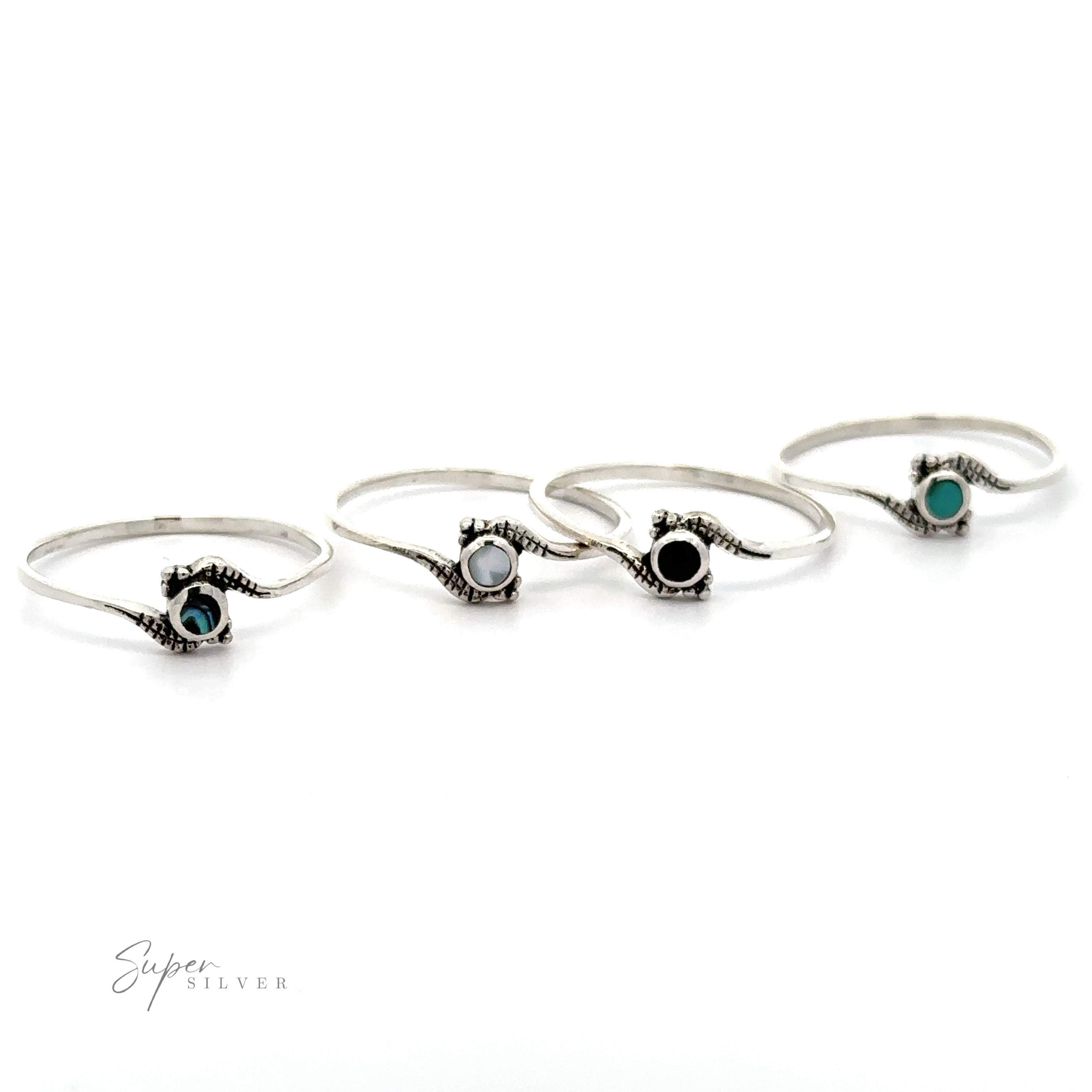 Four Tiny Freeform Rings with Round Inlaid Stones, including turquoise and mother of pearl, displayed in a row against a white background.