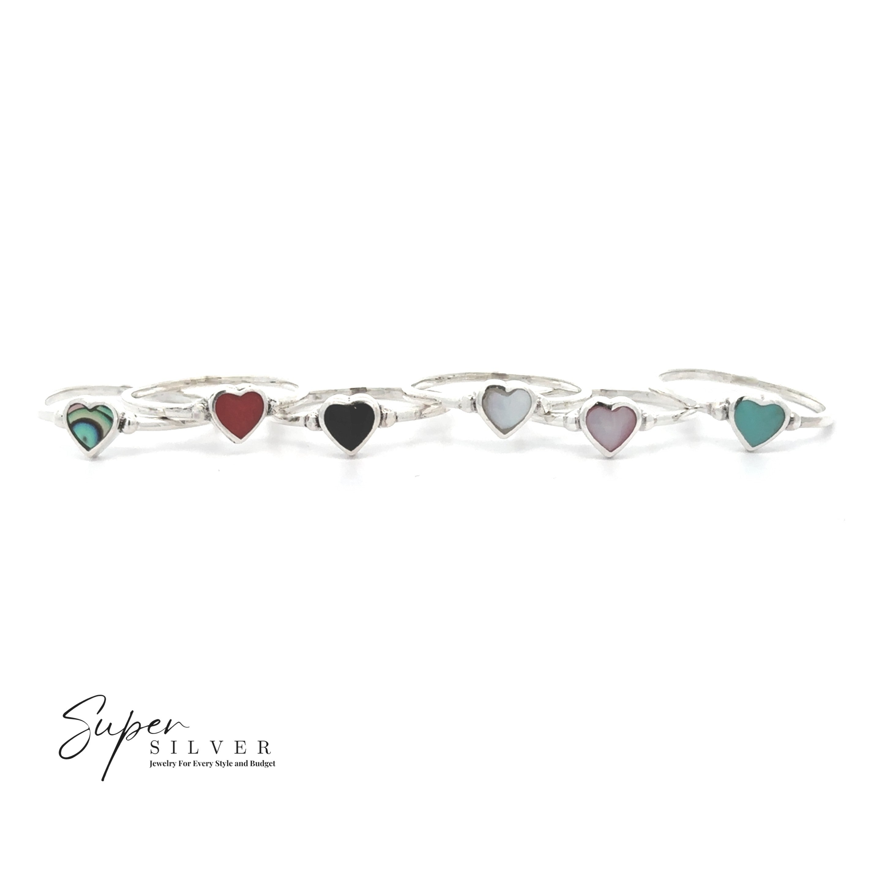 Five Dainty Inlaid Heart Rings, each featuring a small, colorful heart-shaped stone set in sterling silver, are arranged in a row on a white background. The Super Silver logo appears in the bottom left corner.