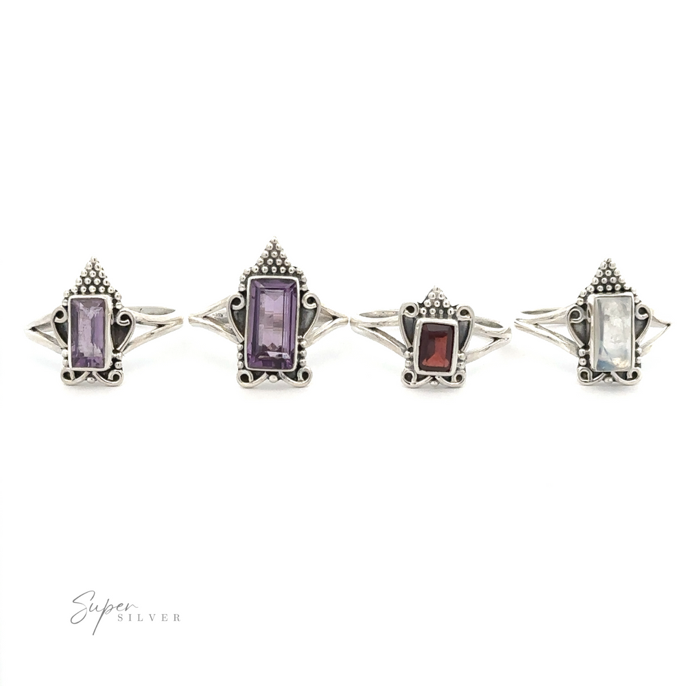 Four Bohemian Princess Rings with rectangular gemstones, including an amethyst and moonstone, in various colors displayed in a line on a white background. The gemstones are purple, dark purple, red, and clear. Perfect for adding a touch of Boho-style princess charm to any outfit.