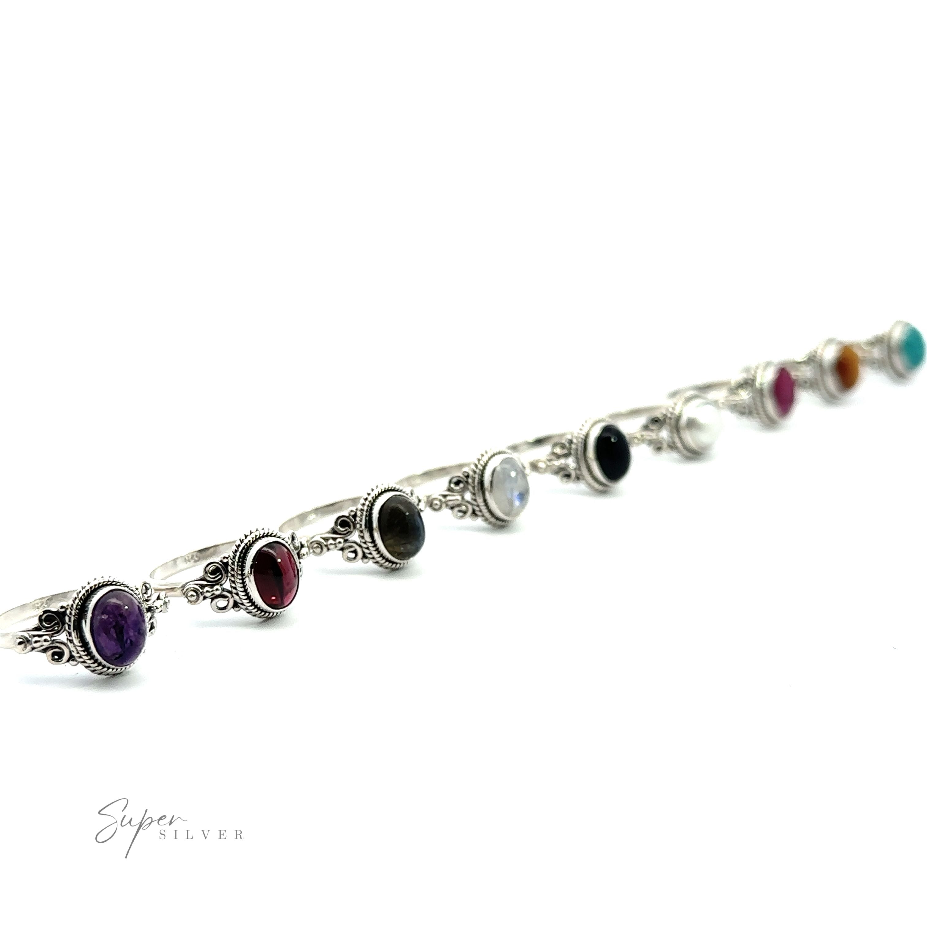 A diagonal array of Sterling Silver rings with various colored Natural Oval Gemstone Rings with Intricate Rope and Long Spiral Border on a white background.