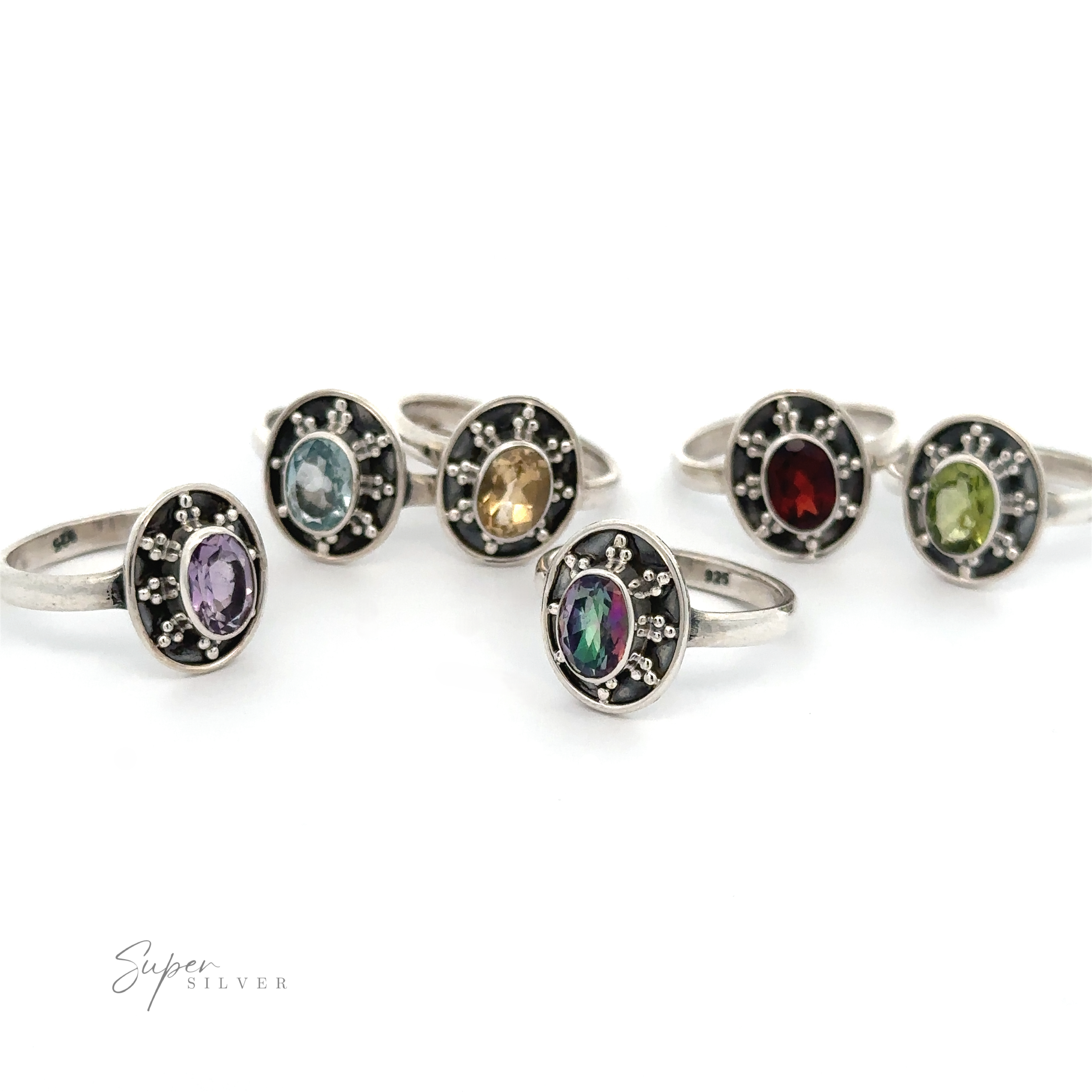 Six Oval Gemstone Rings with Ball and Disk Border in different colors (purple, blue, yellow, red, green) set in circular black bases are arranged in two rows. The words "Super Silver" are in the bottom left corner. These vintage-inspired jewelry pieces add a touch of elegance to any ensemble.