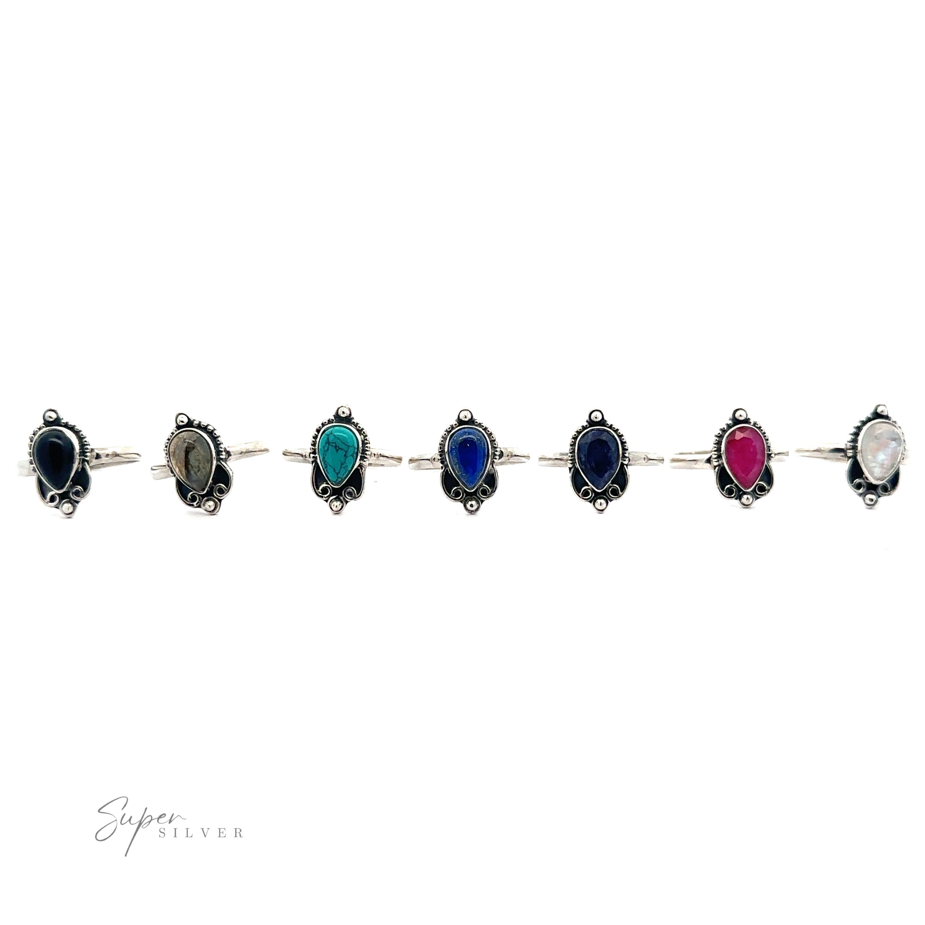 A Vintage Inspired Teardrop Gemstone Ring with alternating oval gemstones in black, green, blue, red, and white, set against a white background.