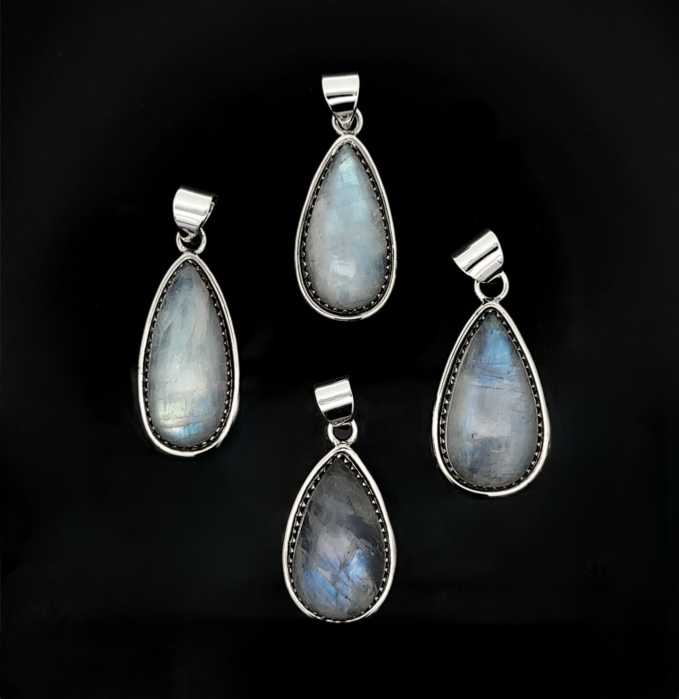 Four Teardrop Moonstone Pendants with sterling silver settings and boho details are arranged on a black background.
