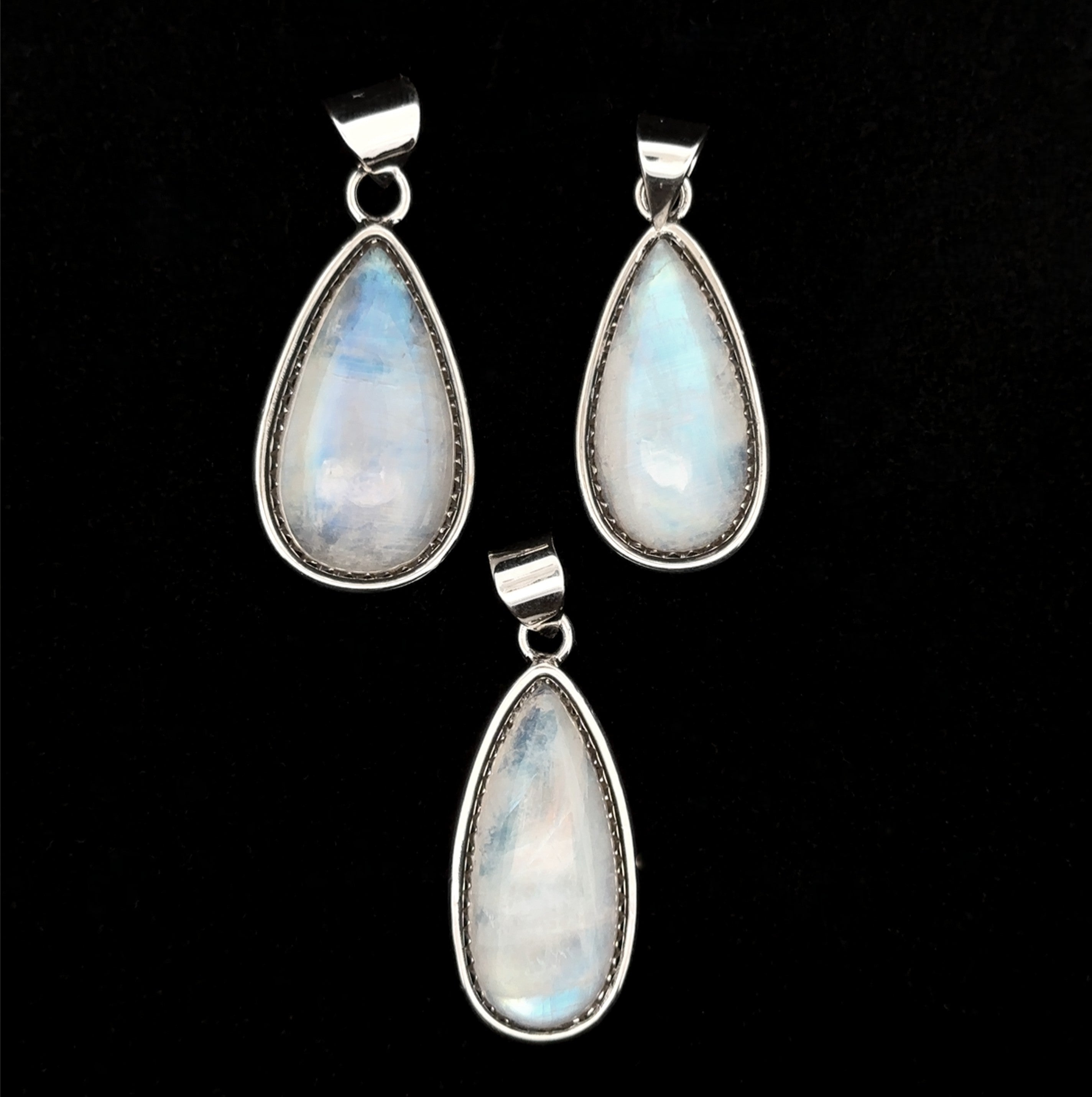 Three Teardrop Moonstone Pendants set in sterling silver with subtle boho details, shown against a black background.