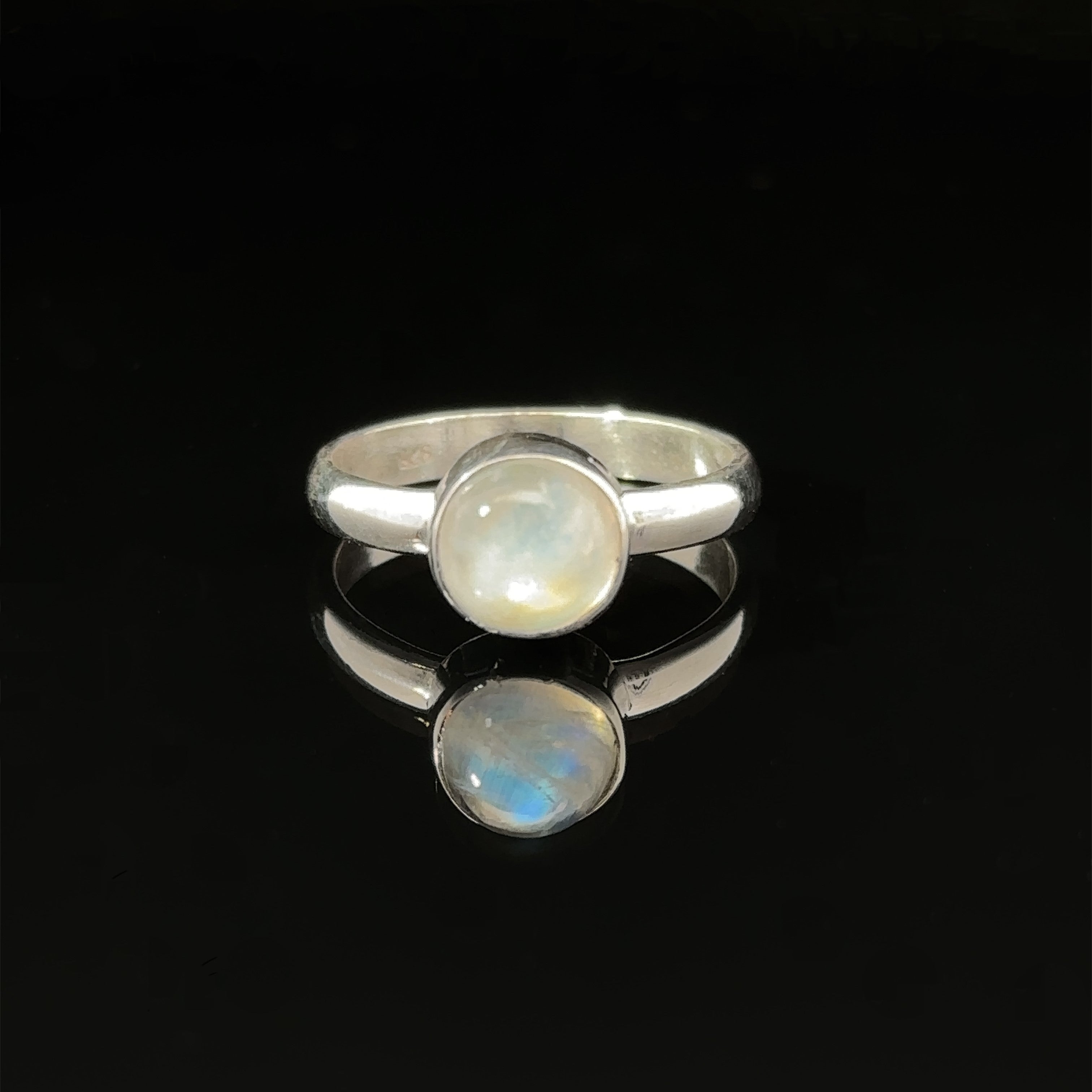 Round Moonstone Ring with a .925 Sterling Silver band reflected on a dark surface.