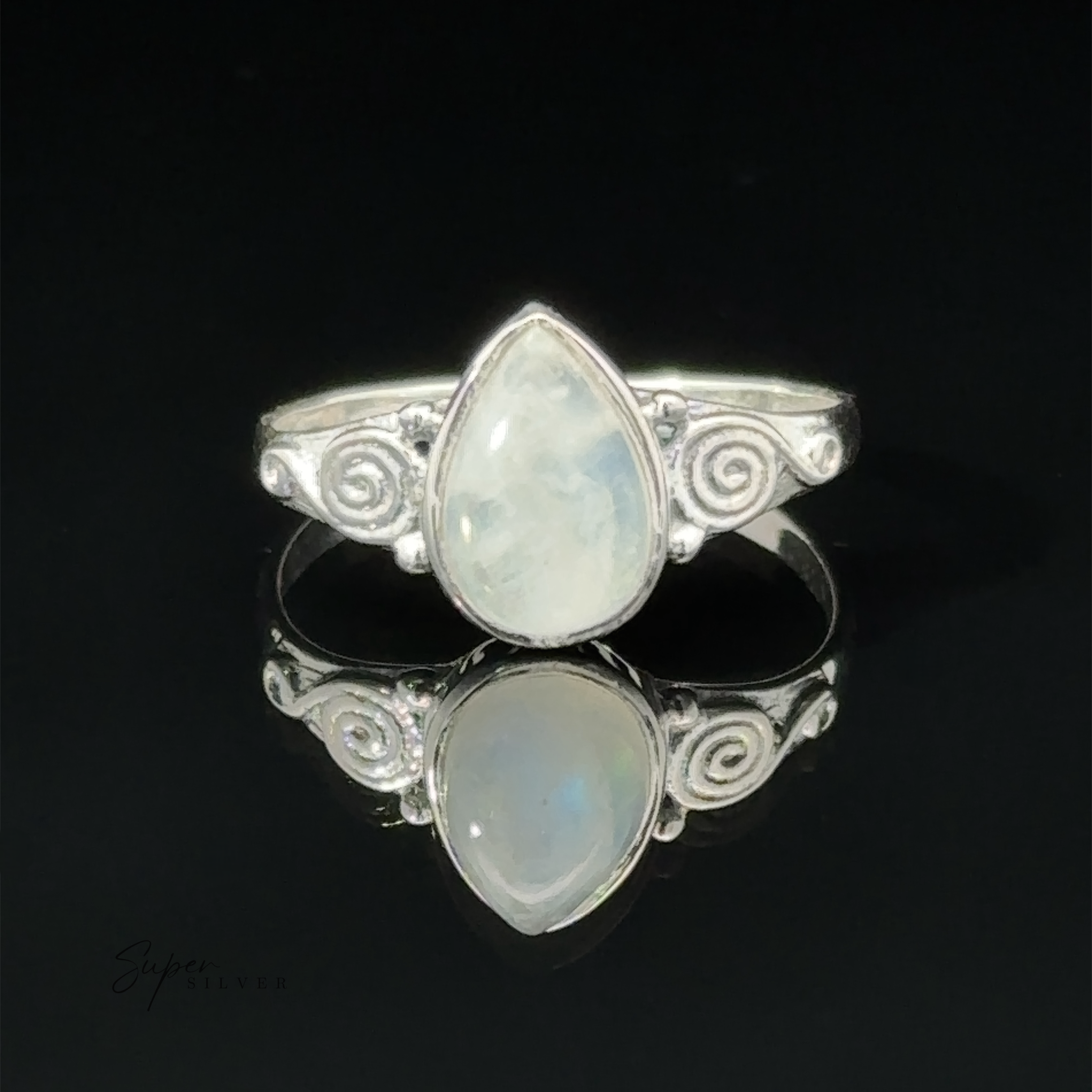 Teardrop Gemstone Ring With Swirls with a teardrop opal set in an intricate design, displayed on a reflective black surface.