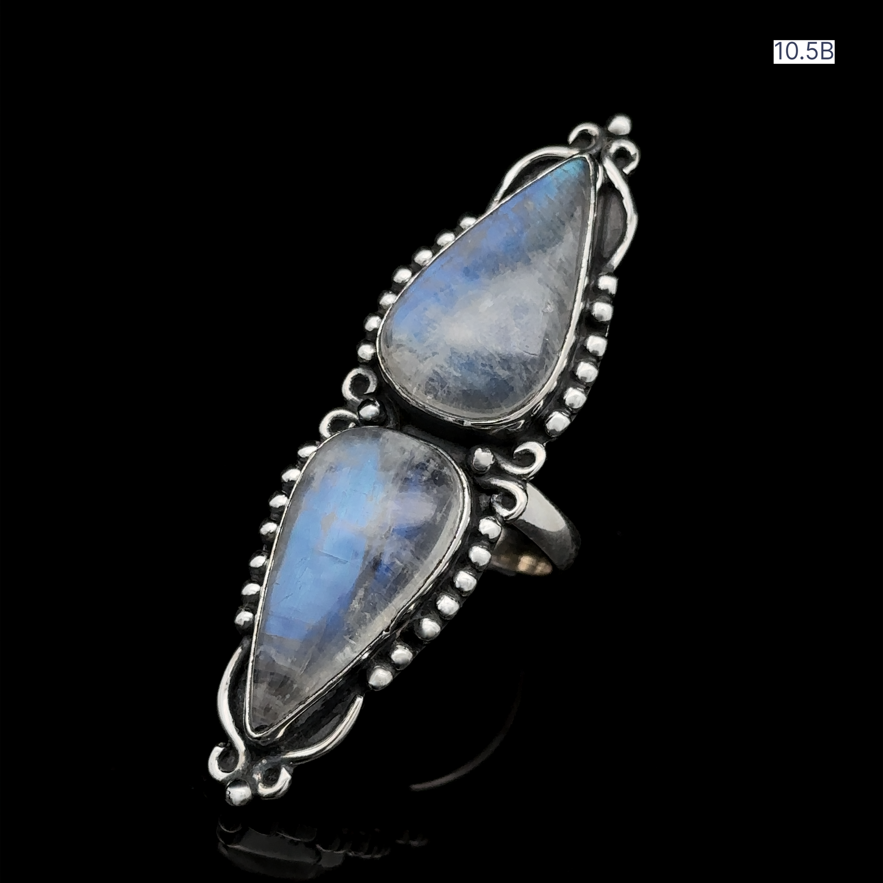 The Long Double Teardrop Moonstone Ring is a striking sterling silver statement piece featuring two vertically set teardrop-shaped moonstone gemstones with intricate detailing, displayed on a black background.