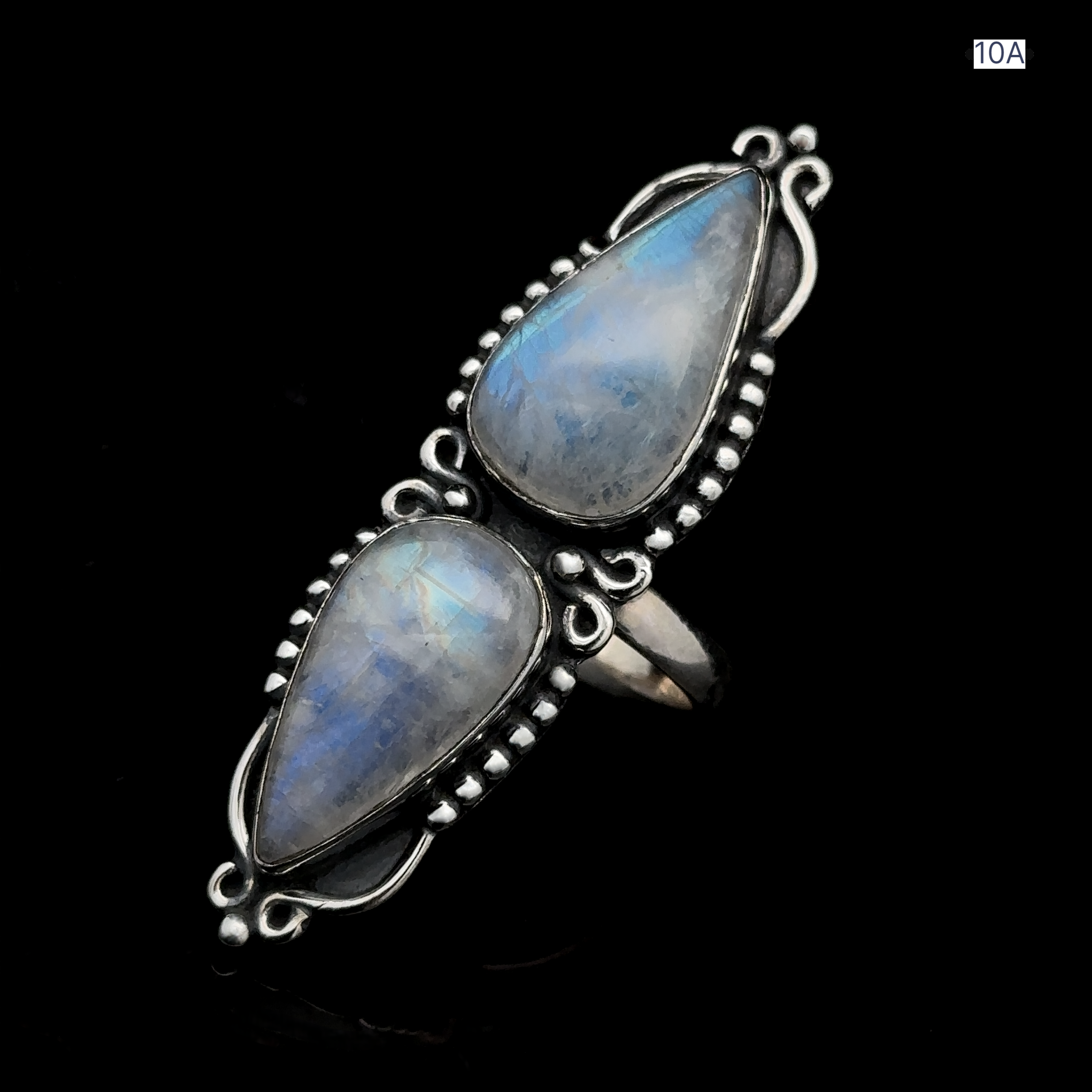 The Long Double Teardrop Moonstone Ring, featuring two pear-shaped moonstone gems set in an ornate sterling silver design, is showcased against a black background.