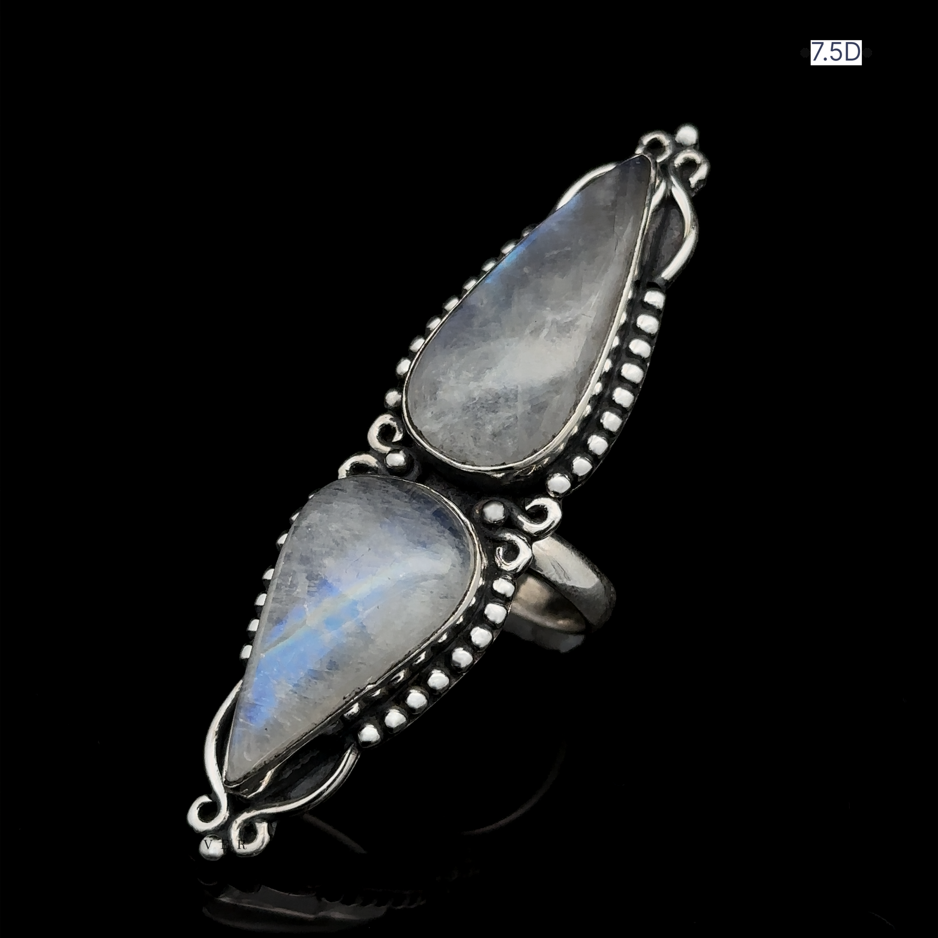 The Long Double Teardrop Moonstone Ring showcases two teardrop-shaped moonstone gemstones set in an ornate sterling silver design, beautifully displayed against a black background.