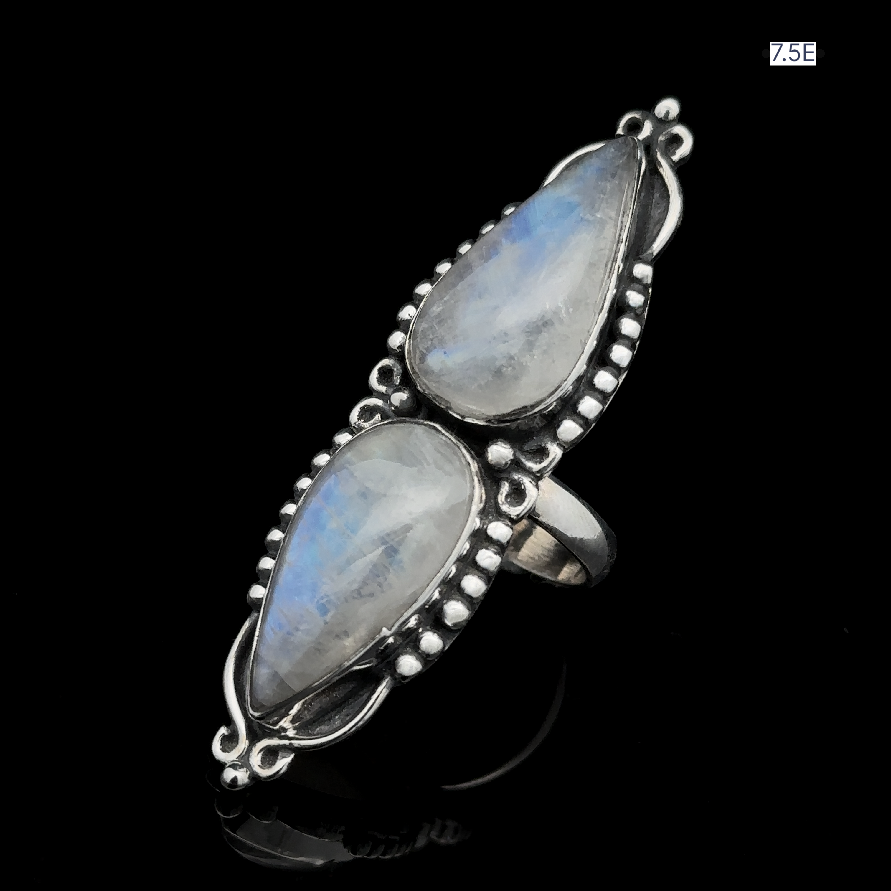 Introducing the Long Double Teardrop Moonstone Ring: A stunning statement piece adorned with two large, teardrop-shaped moonstone gems set vertically in sterling silver, featuring intricate beadwork on a black background. Available in size 7.5.