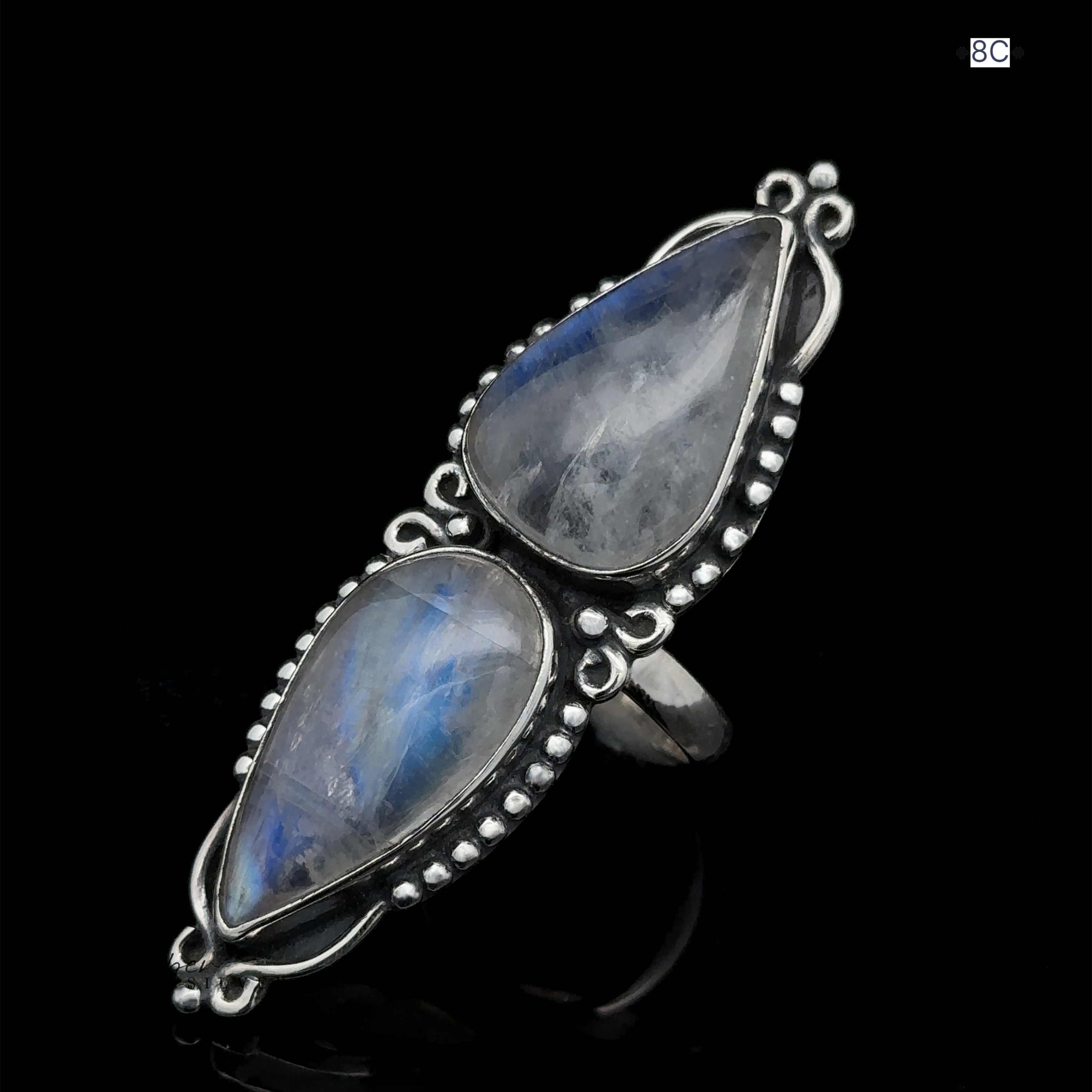 A stunning Long Double Teardrop Moonstone Ring, crafted from sterling silver and featuring two large, teardrop-shaped moonstone gems set in an elaborate bezel with delicate silver ball accents, displayed against a black background.