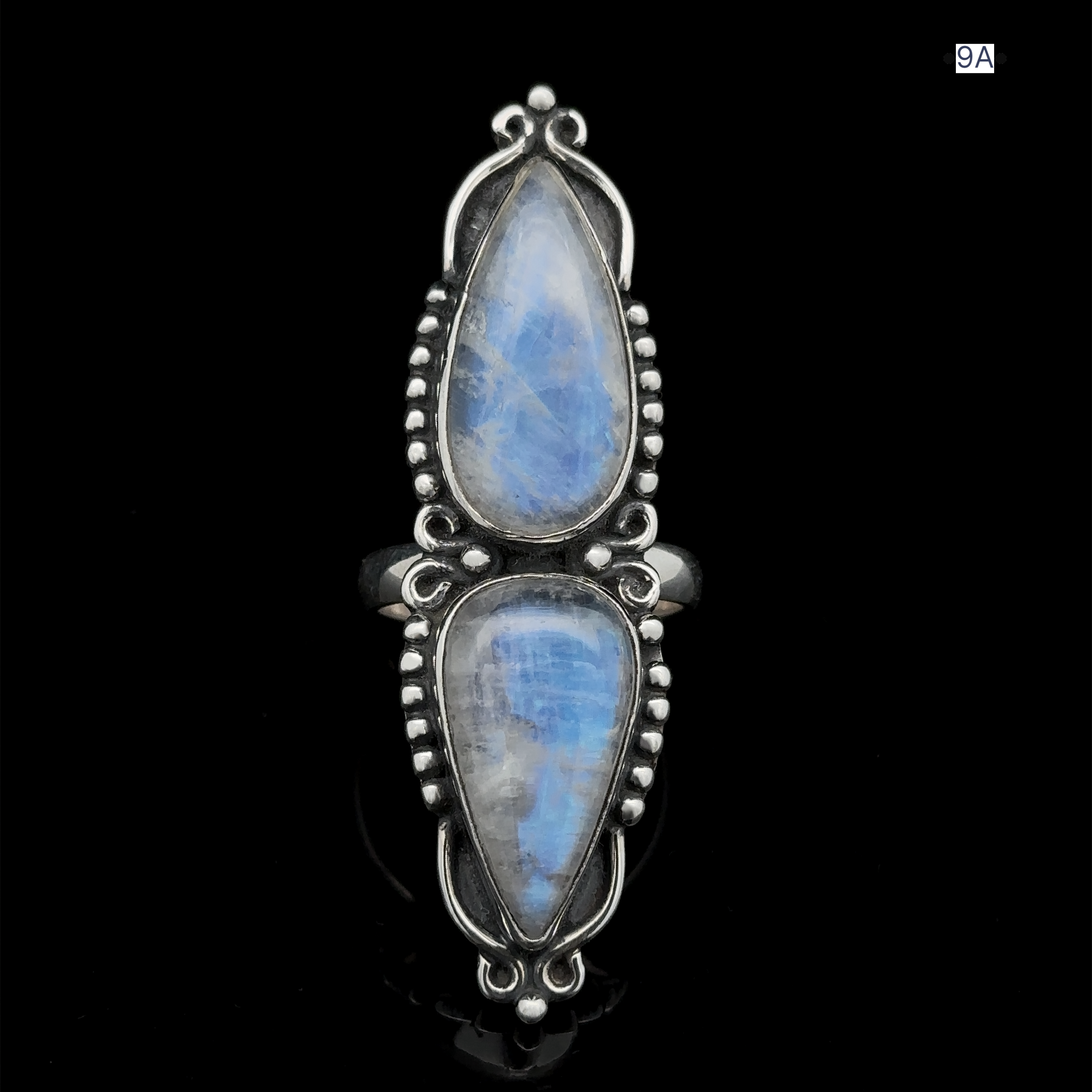 The Long Double Teardrop Moonstone Ring showcases two sizable, teardrop-shaped moonstones set vertically in a sterling silver band adorned with detailed beading.