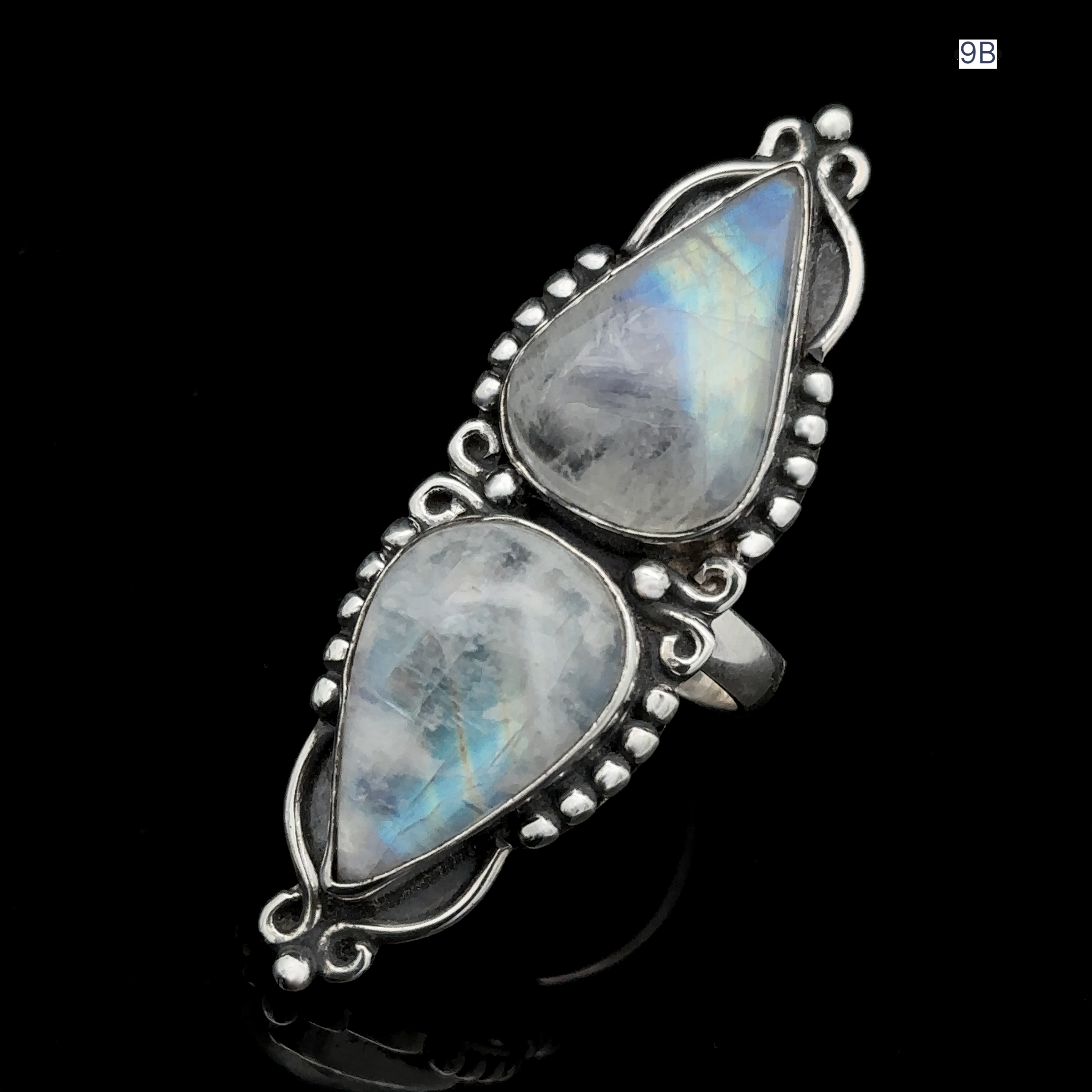 Displayed on a black background, the Long Double Teardrop Moonstone Ring features a decorative sterling silver setting.