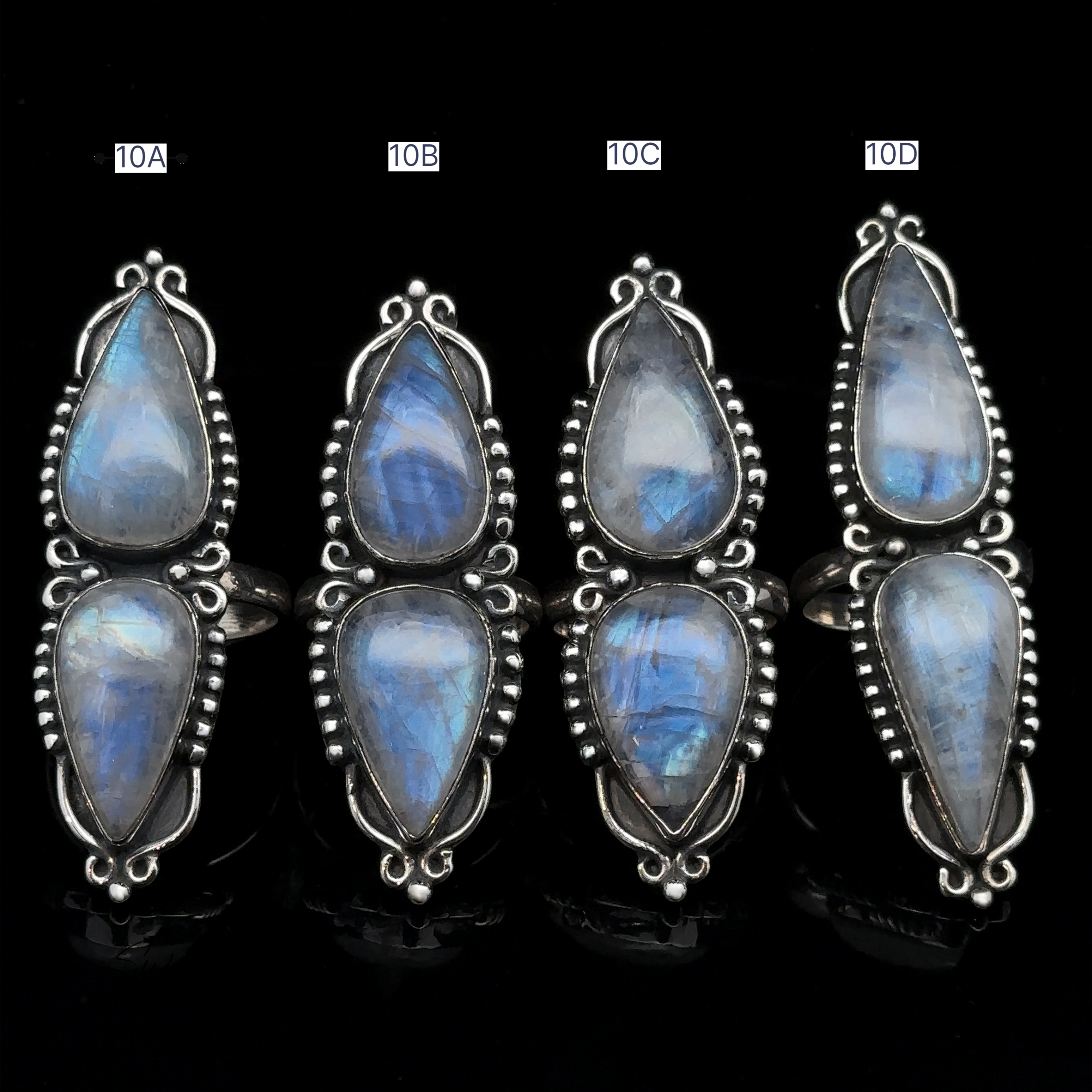 Four Long Double Teardrop Moonstone Rings, labeled 10A, 10B, 10C, and 10D, are arranged in a row against a black background. Each statement ring gleams elegantly, showcasing the exquisite craftsmanship and stunning allure of moonstone.