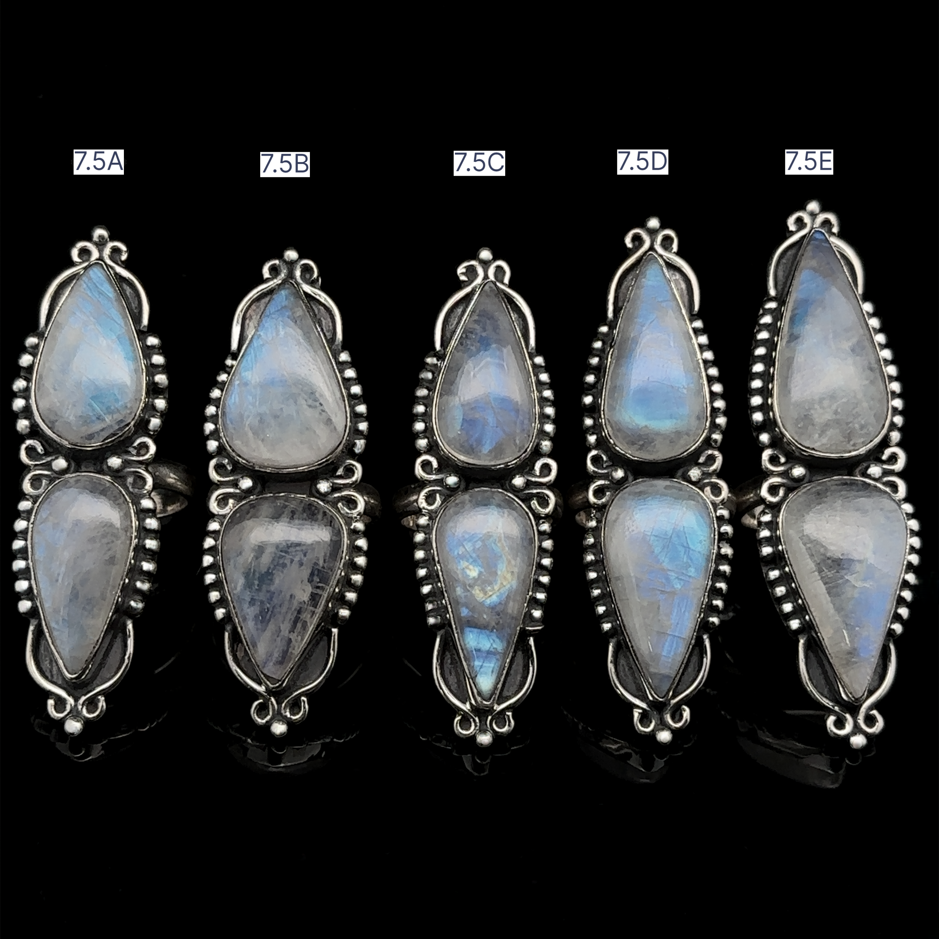 A single Long Double Teardrop Moonstone Ring, displayed on a black background. The ring features dual teardrop-shaped moonstones with intricate sterling silver detailing around the stones.