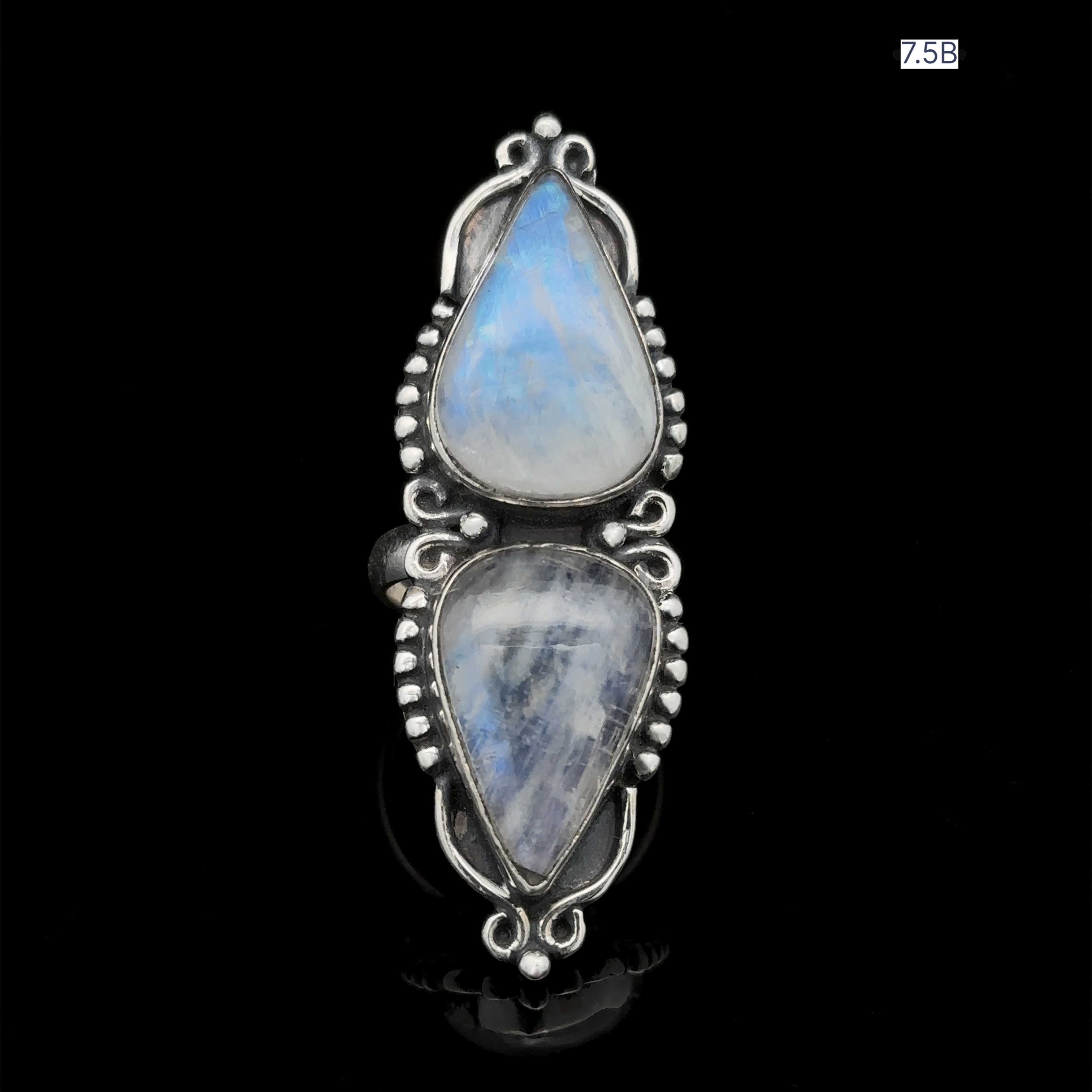Long Double Teardrop Moonstone Ring featuring two vertically aligned teardrop-shaped moonstones on a black background. The intricate metalwork detailing is crafted from sterling silver, and the ring is labeled "7.5B" in the top right corner.