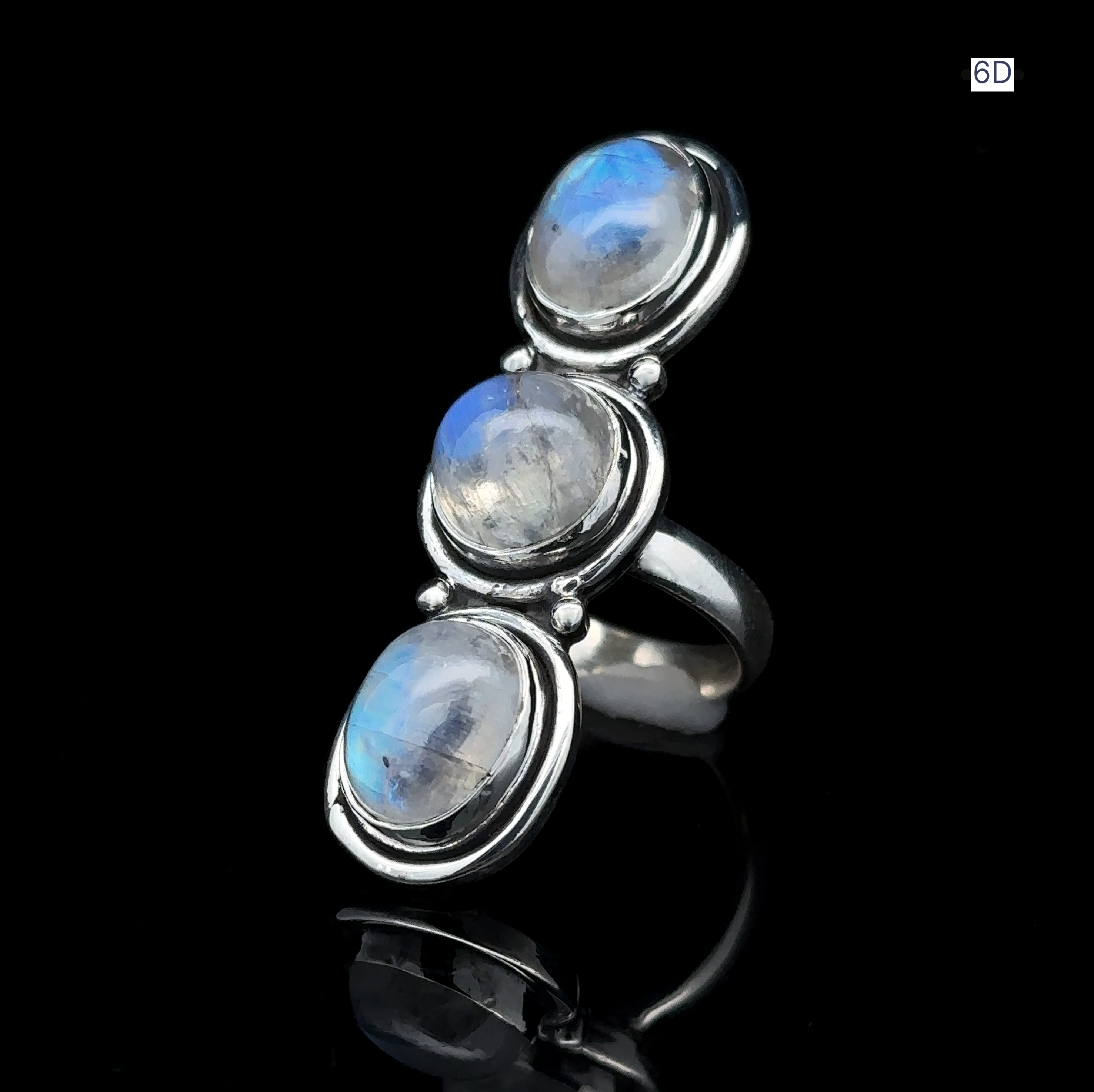 The Triple Moonstone Ring showcases three round moonstone gems set vertically against a black backdrop, exuding goddess energy.