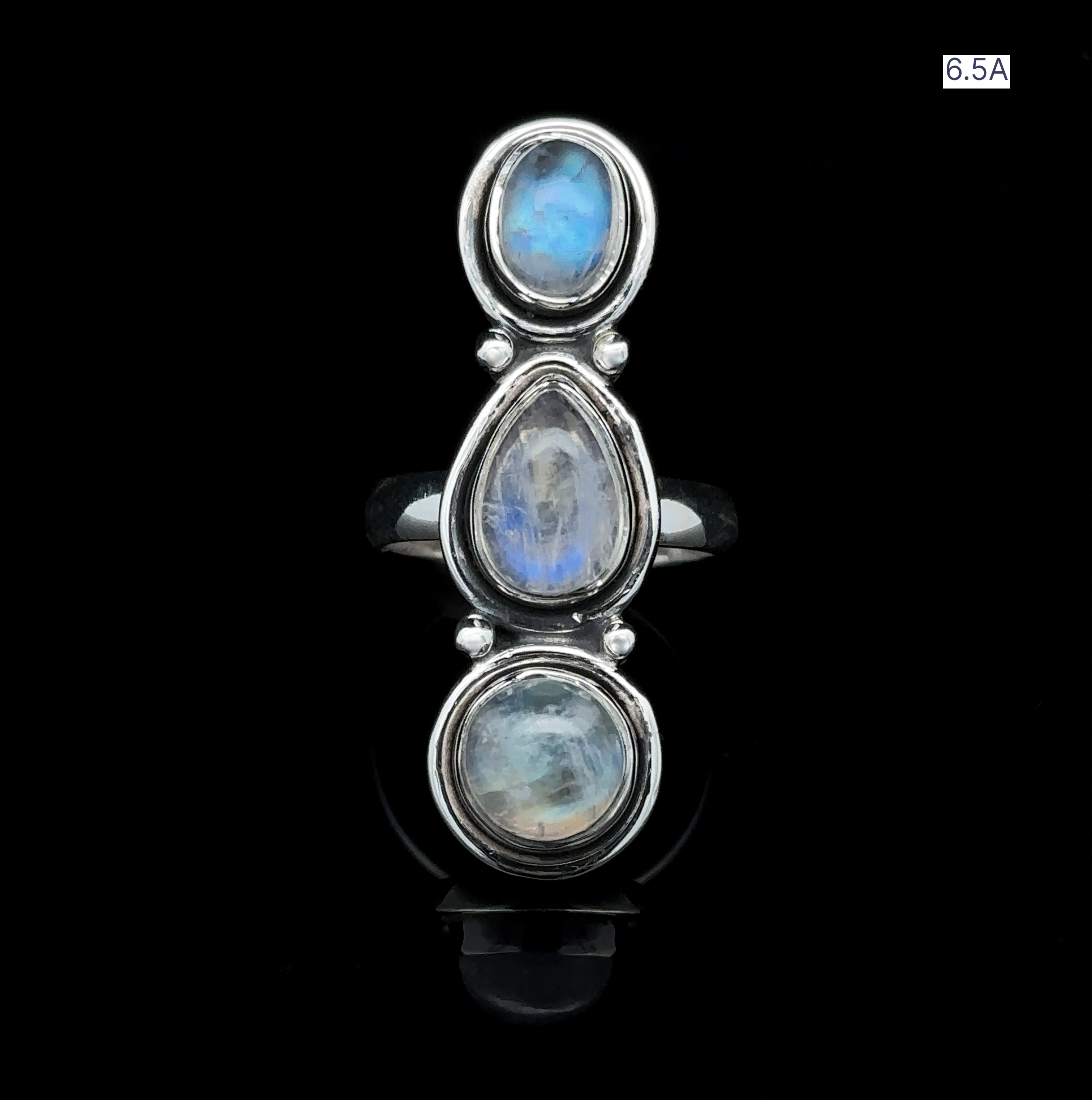 The Triple Moonstone Ring showcases three vertically stacked oval moonstones set against a black background, radiating goddess energy. Elegantly labeled in the top right corner is Size 6.5A.
