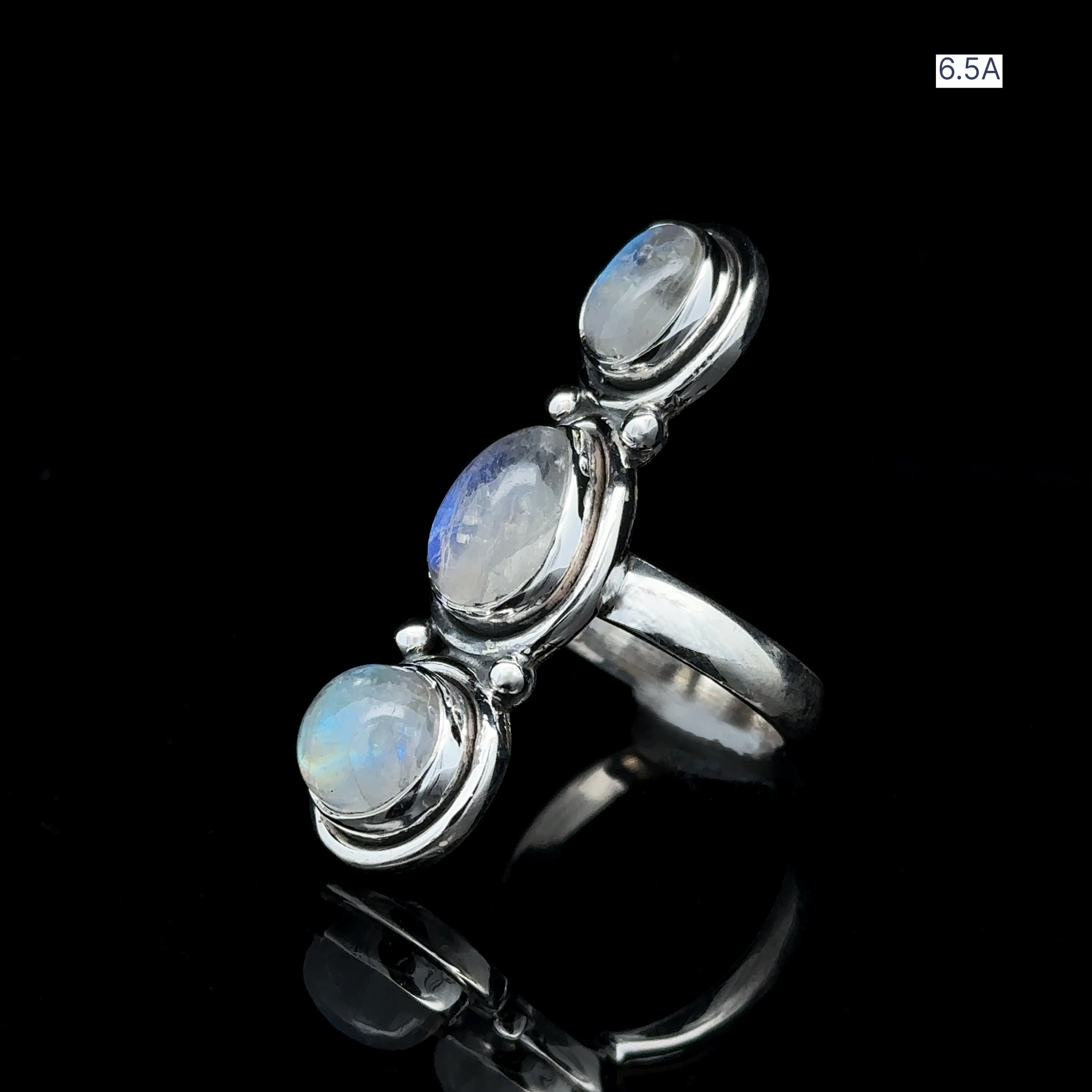 Triple Moonstone Ring crafted in sterling silver, featuring three round moonstones set against a black backdrop that exudes goddess energy. Marked with "6.5A" in the upper right corner.