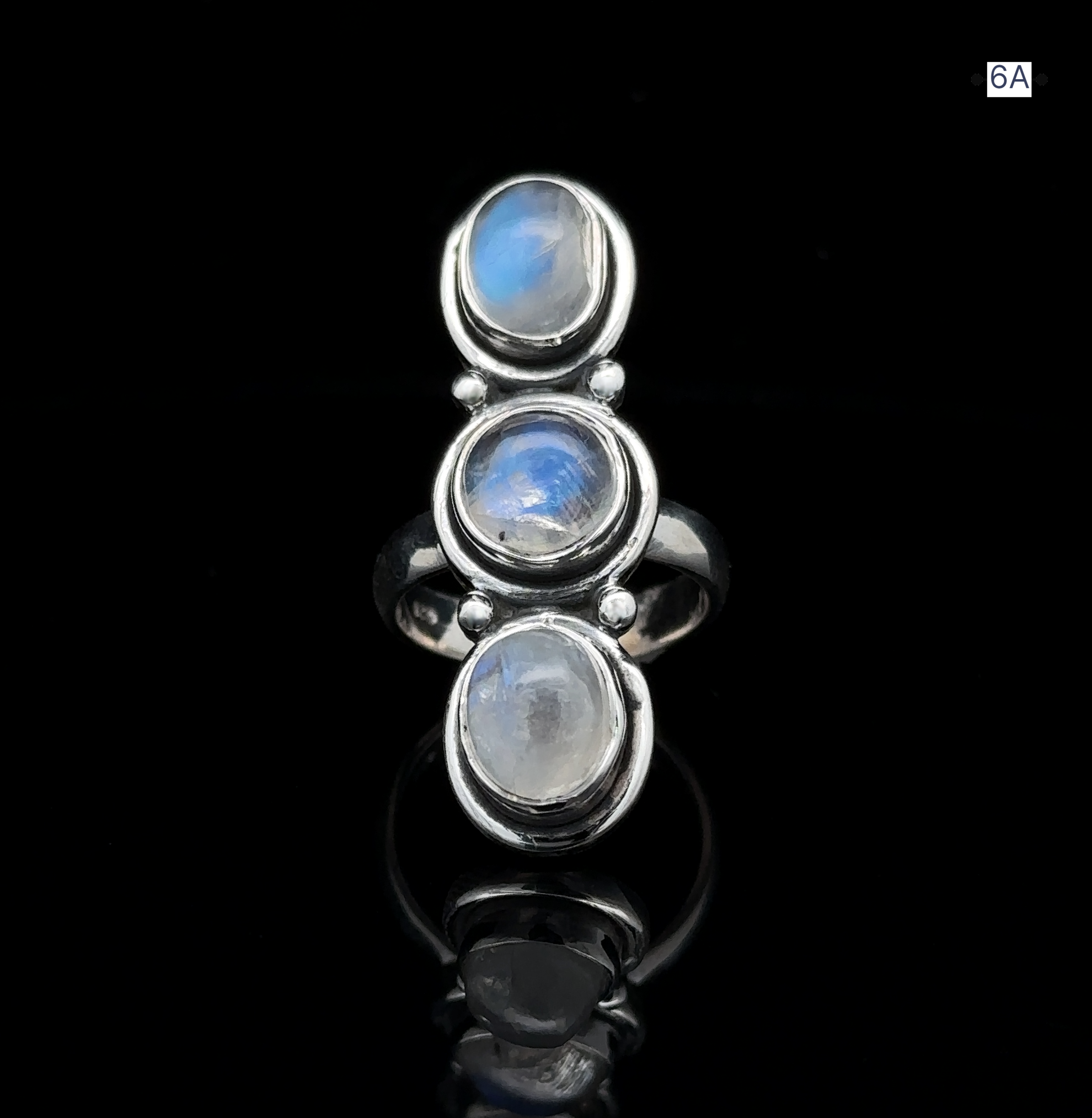 Triple Moonstone Ring crafted from sterling silver, showcasing three oval moonstone settings that exude goddess energy and a reflective surface, beautifully displayed against a black background.