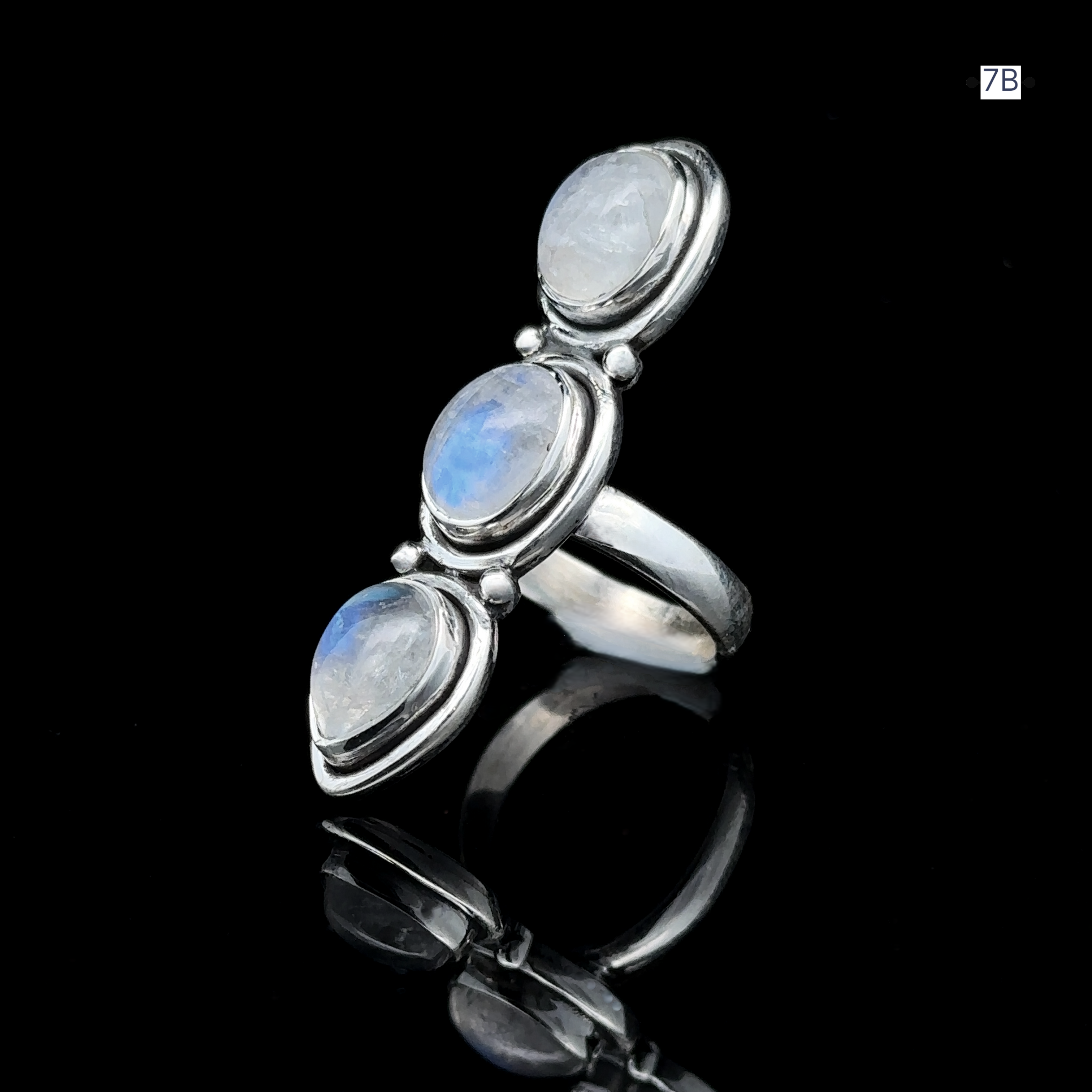 Triple Moonstone Ring showcasing three vertically aligned oval moonstones on a reflective black surface, intricately crafted in sterling silver to evoke goddess energy.