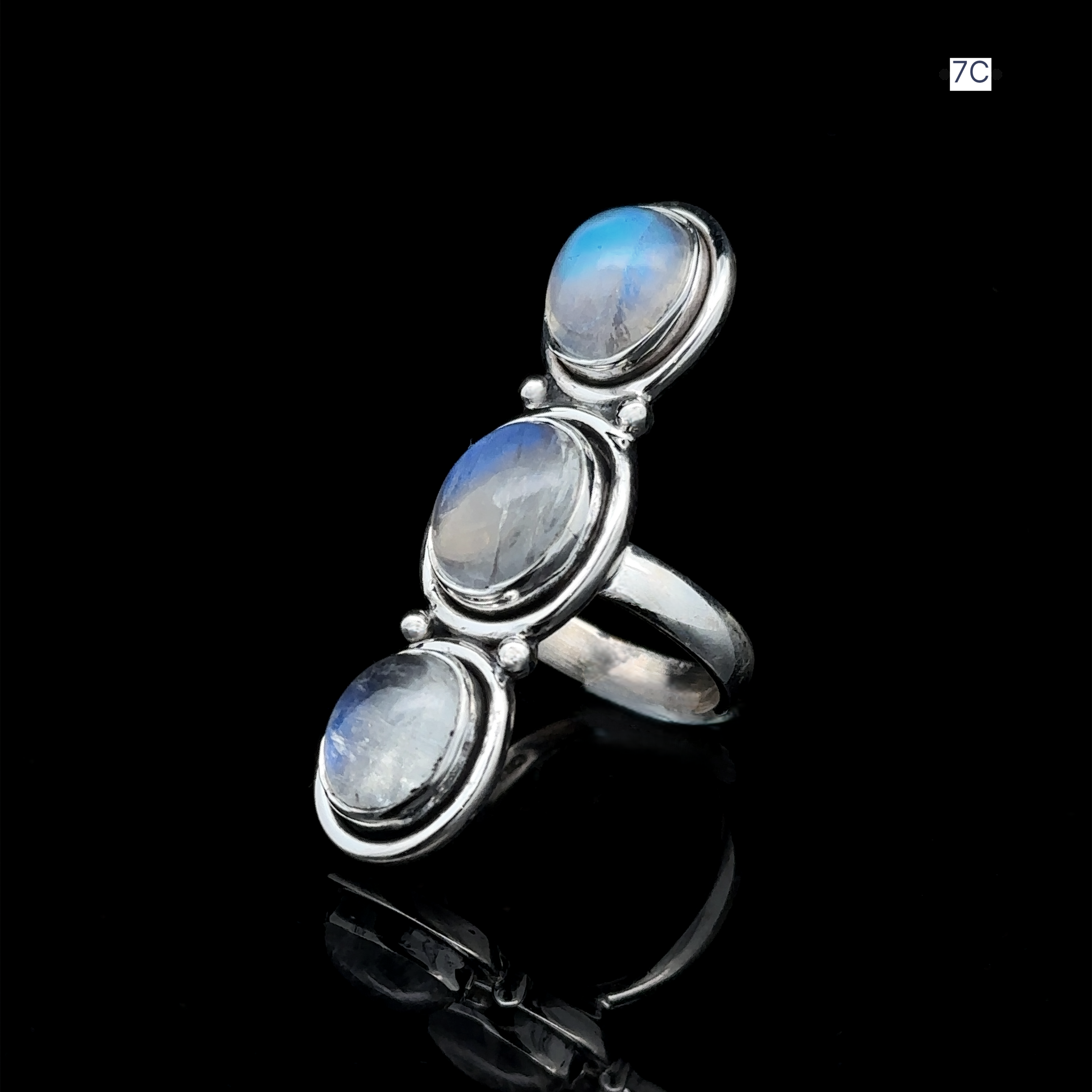 This sterling silver Triple Moonstone Ring showcases three oval moonstone gems arranged vertically on a reflective black surface, capturing the essence of goddess energy.
