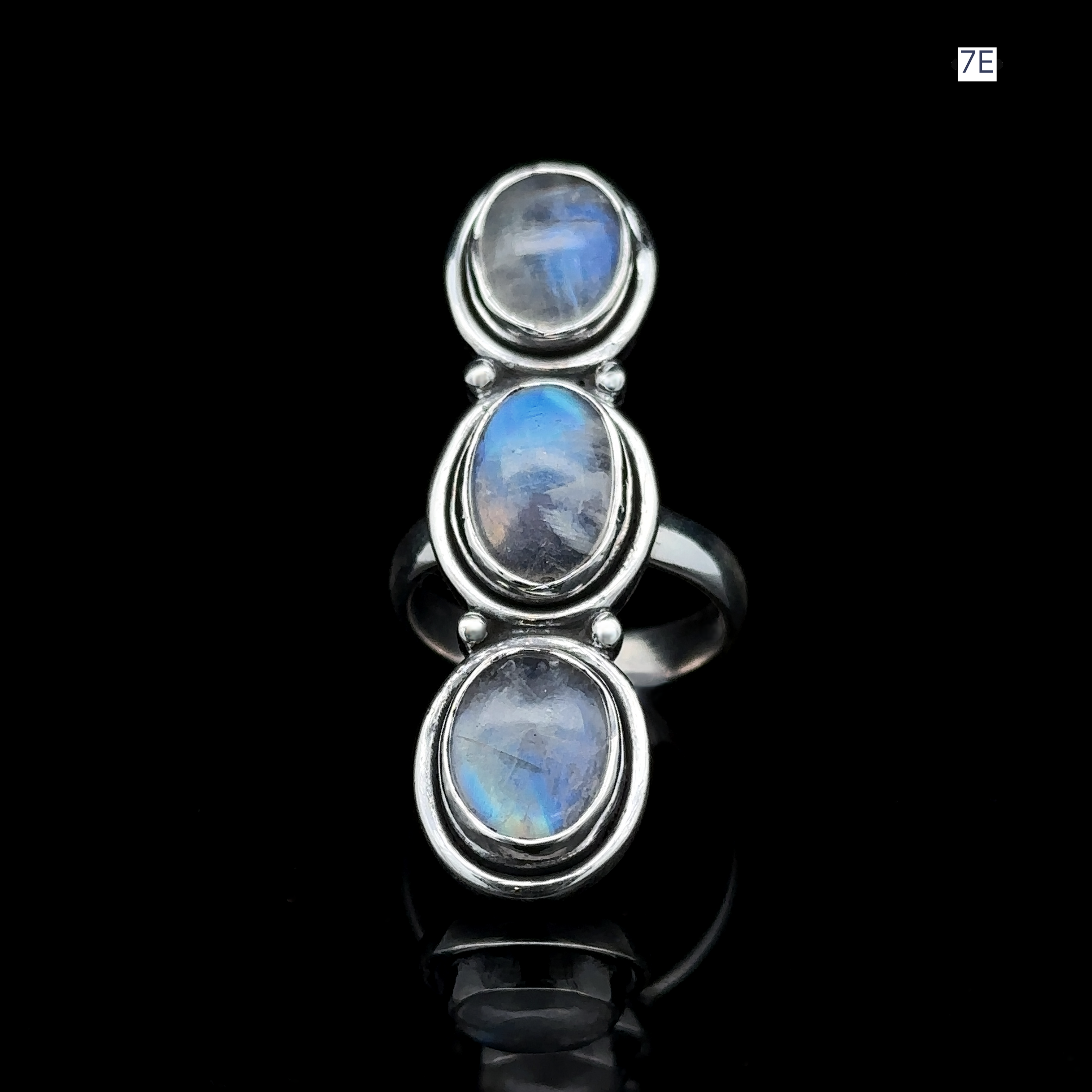 The Triple Moonstone Ring, made of sterling silver and featuring three vertically aligned oval moonstone gems, glows beautifully against a black background, channeling serene goddess energy.