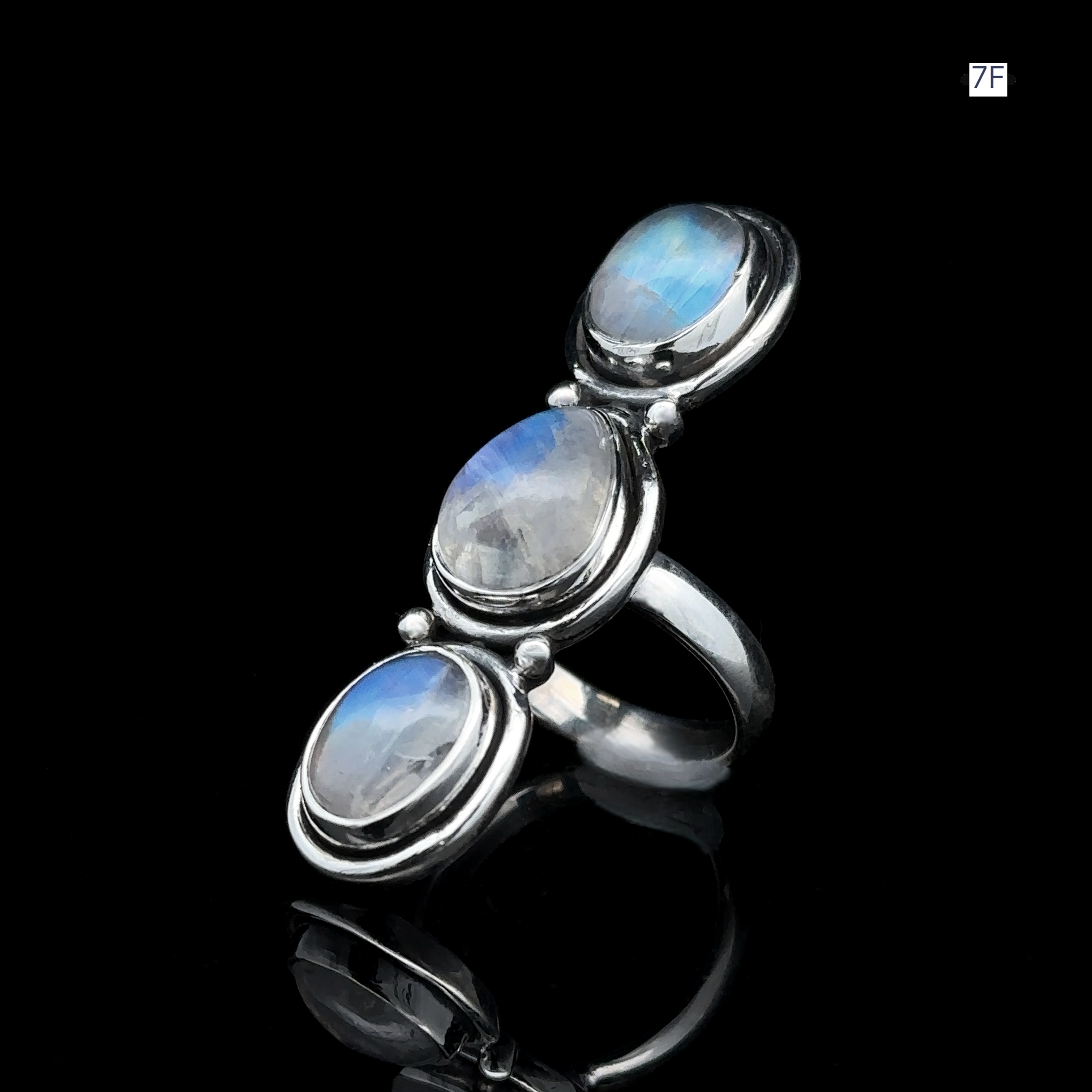 The Triple Moonstone Ring showcases three oval moonstone gemstones set against a dark backdrop, exuding a powerful goddess energy.
