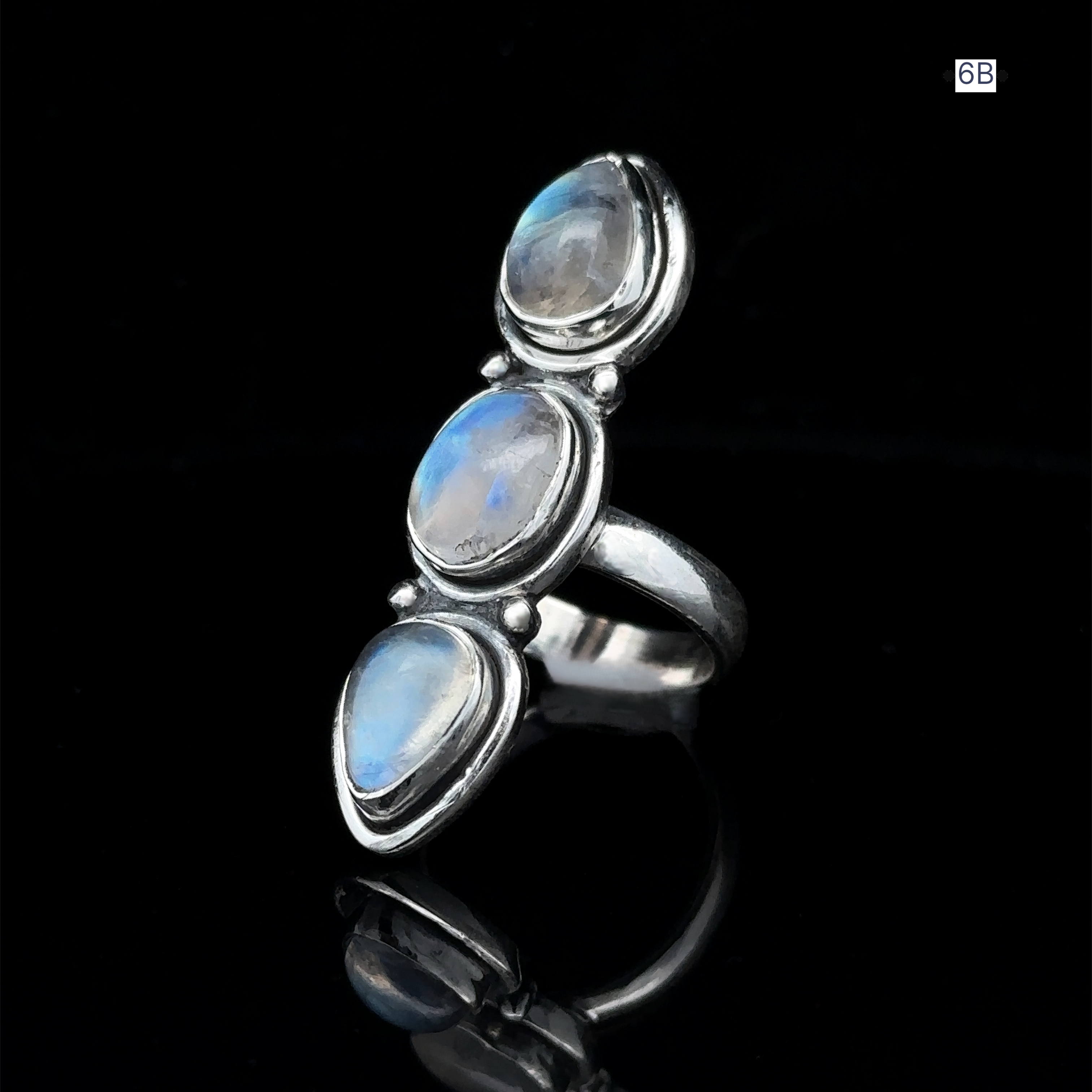 Triple Moonstone Ring crafted from sterling silver, showcasing three oval moonstones on a reflective black surface, channeling goddess energy.