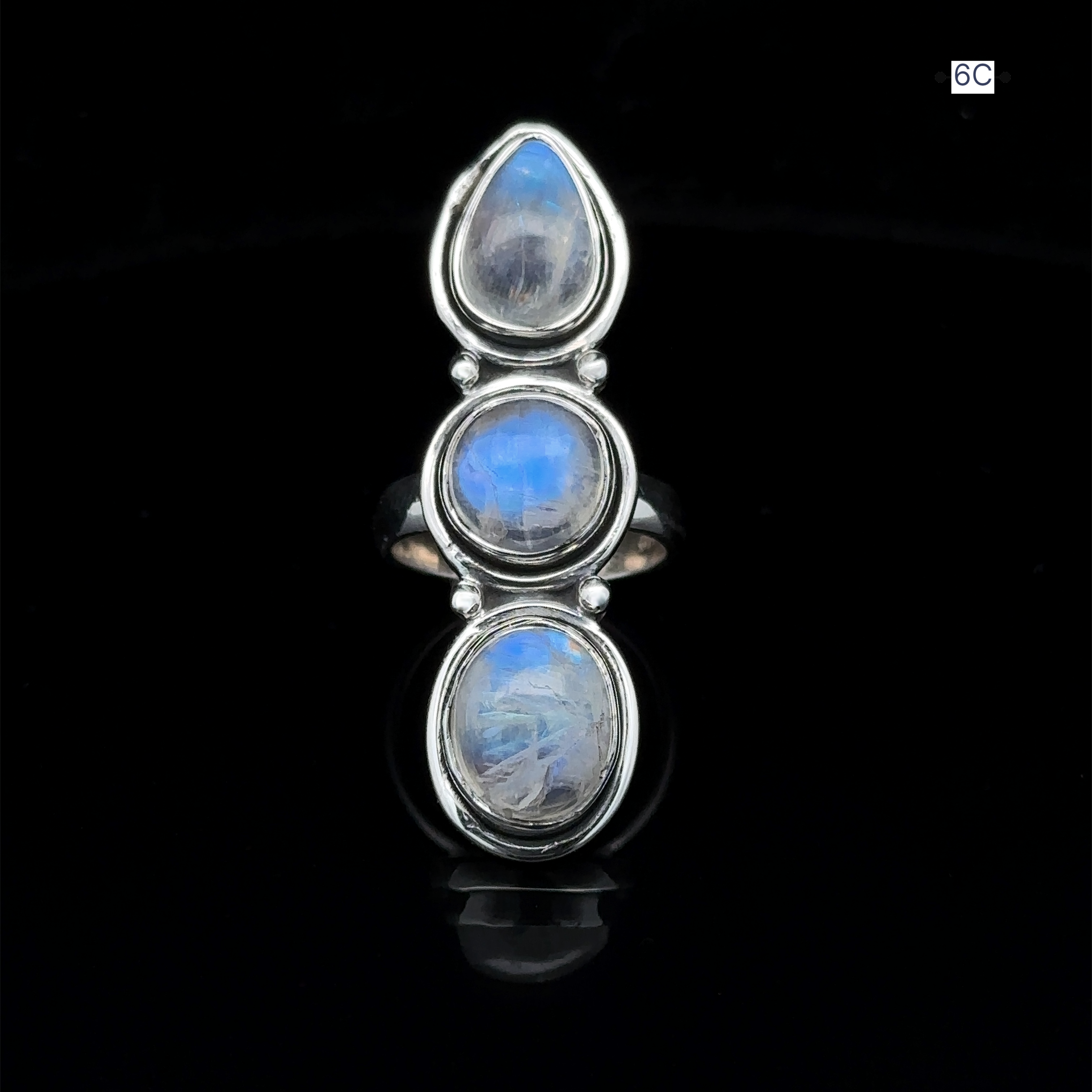 The Triple Moonstone Ring radiates goddess energy, showcasing three enchanting oval moonstone gems arranged in a vertical row against a sleek black background.