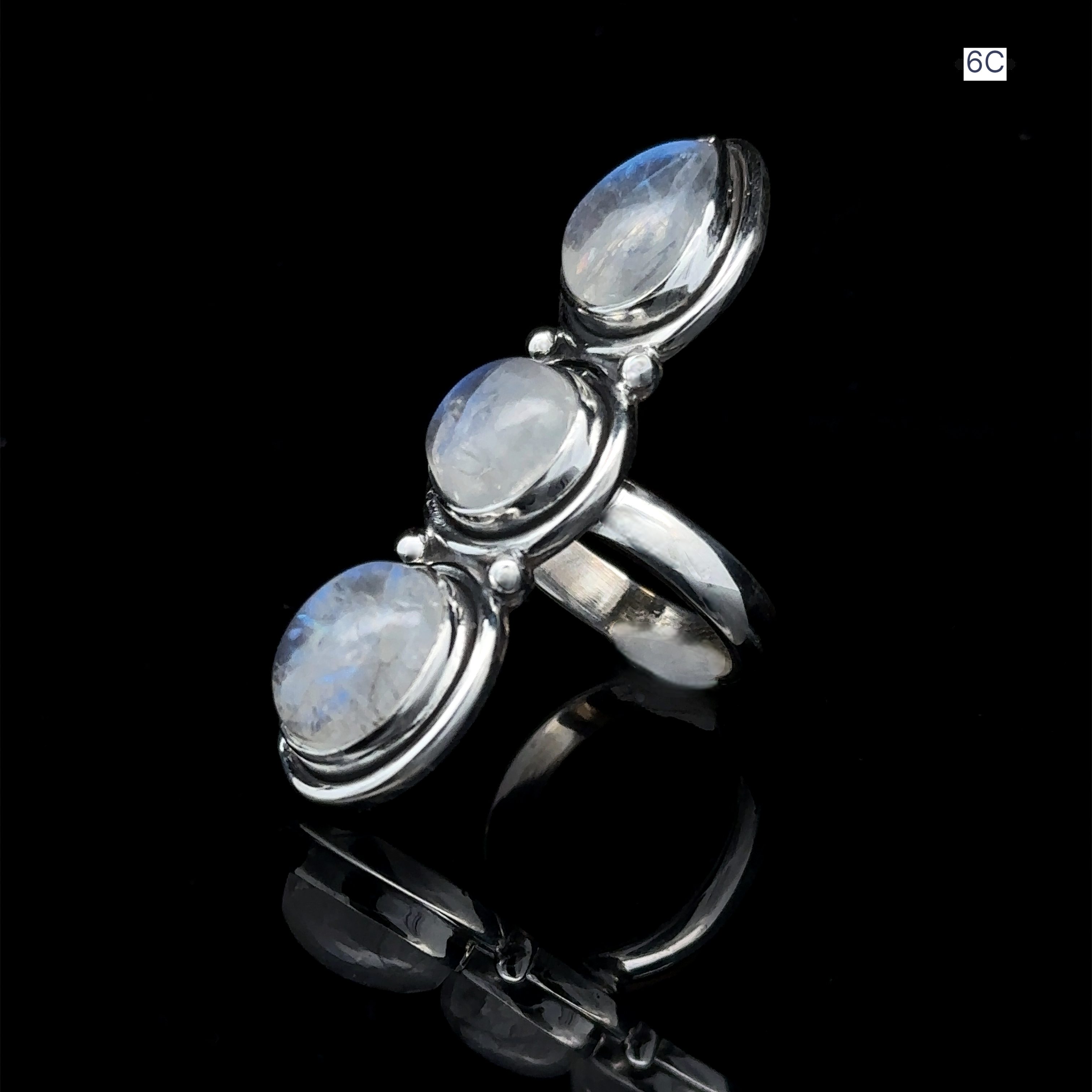 Triple Moonstone Ring showcasing three round moonstone gems arranged in a row, radiating goddess energy on a reflective black surface.