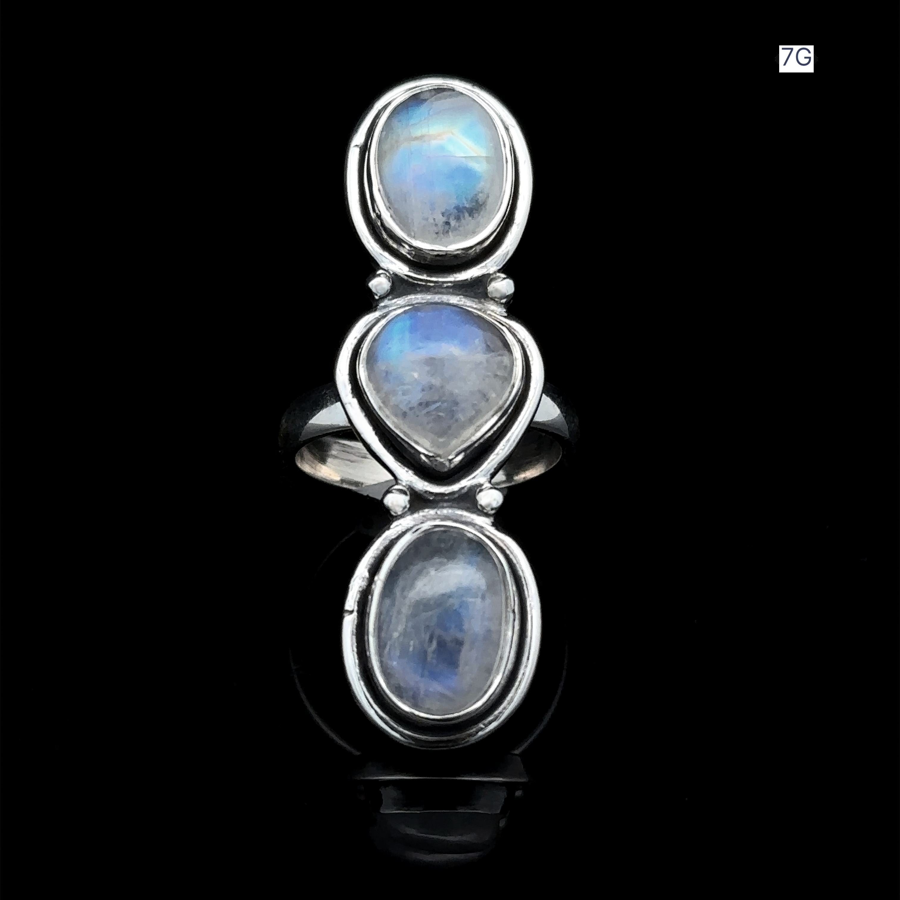 The Triple Moonstone Ring is crafted from sterling silver and showcases three vertically aligned oval moonstones, beautifully channeling goddess energy against a sleek black backdrop.