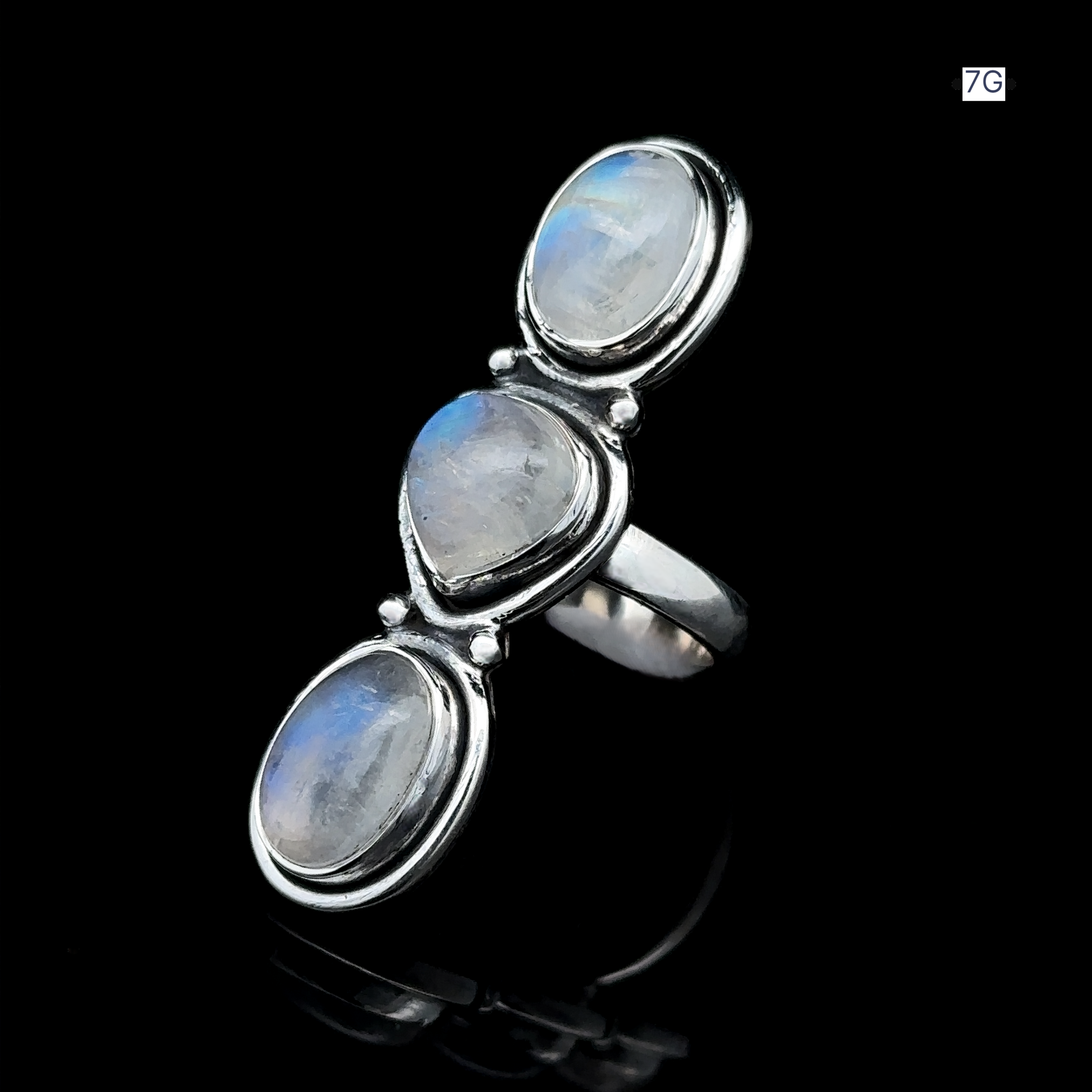 The Triple Moonstone Ring showcases three oval moonstone gems arranged vertically on a black background, embodying goddess energy.