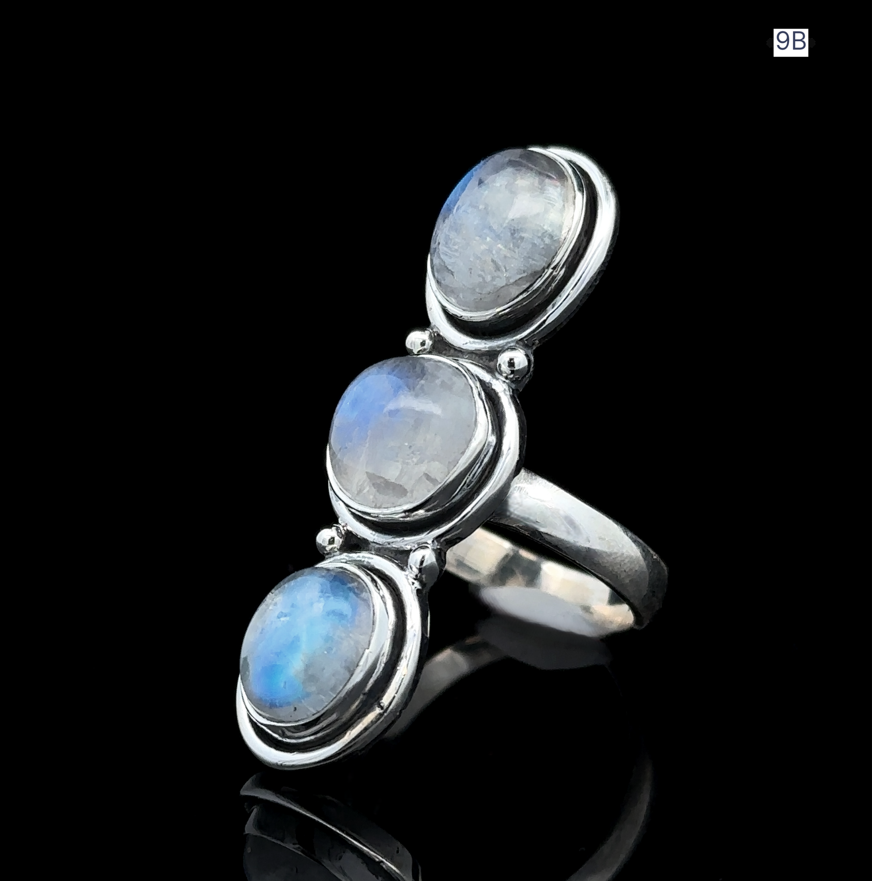 The Triple Moonstone Ring, crafted from sterling silver and featuring three round moonstone cabochons set against a black background, captures the essence of goddess energy.
