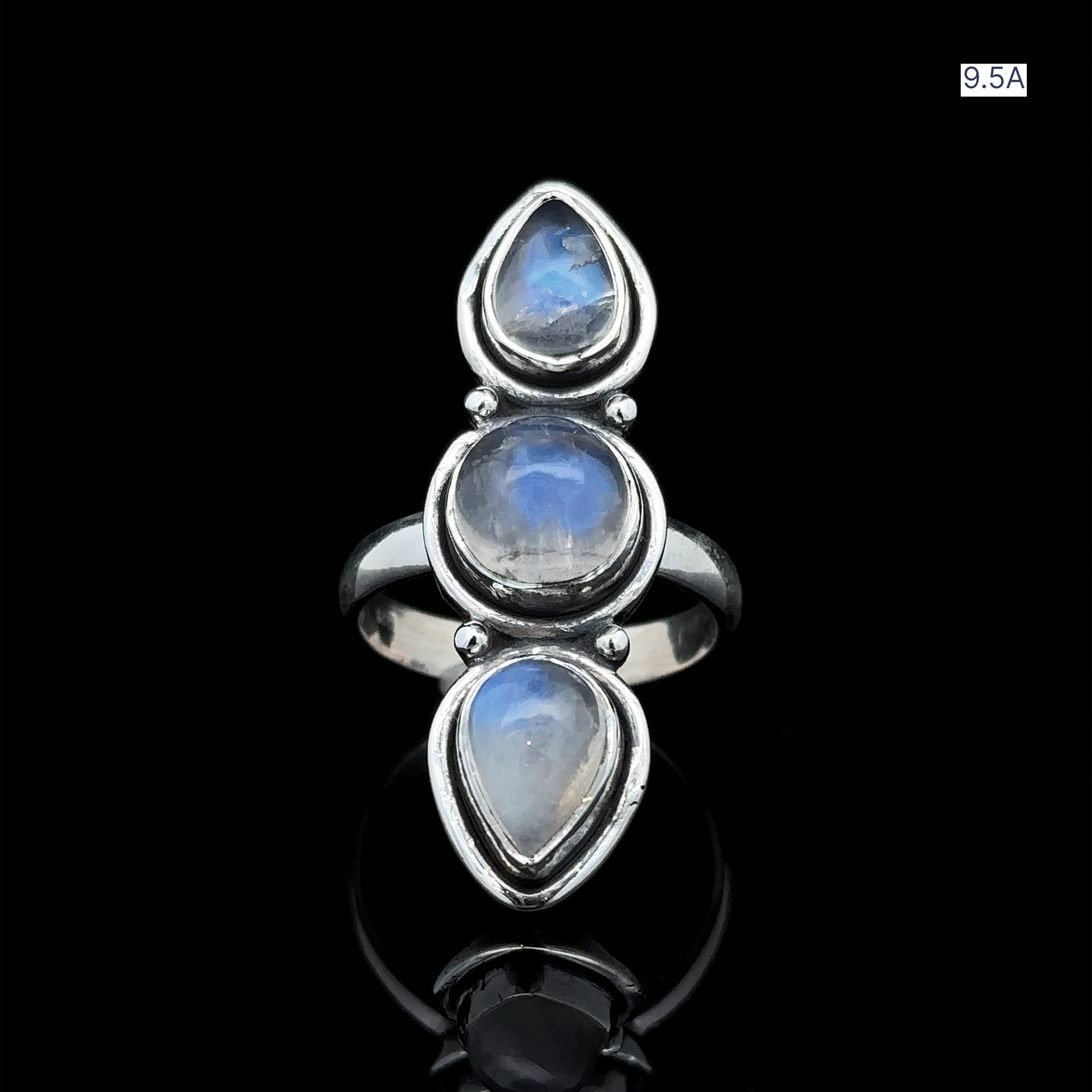 The Triple Moonstone Ring, crafted in sterling silver, showcases three oval moonstone cabochons that radiate goddess energy. Positioned vertically against a black backdrop, this ring is available in size 9.5A.