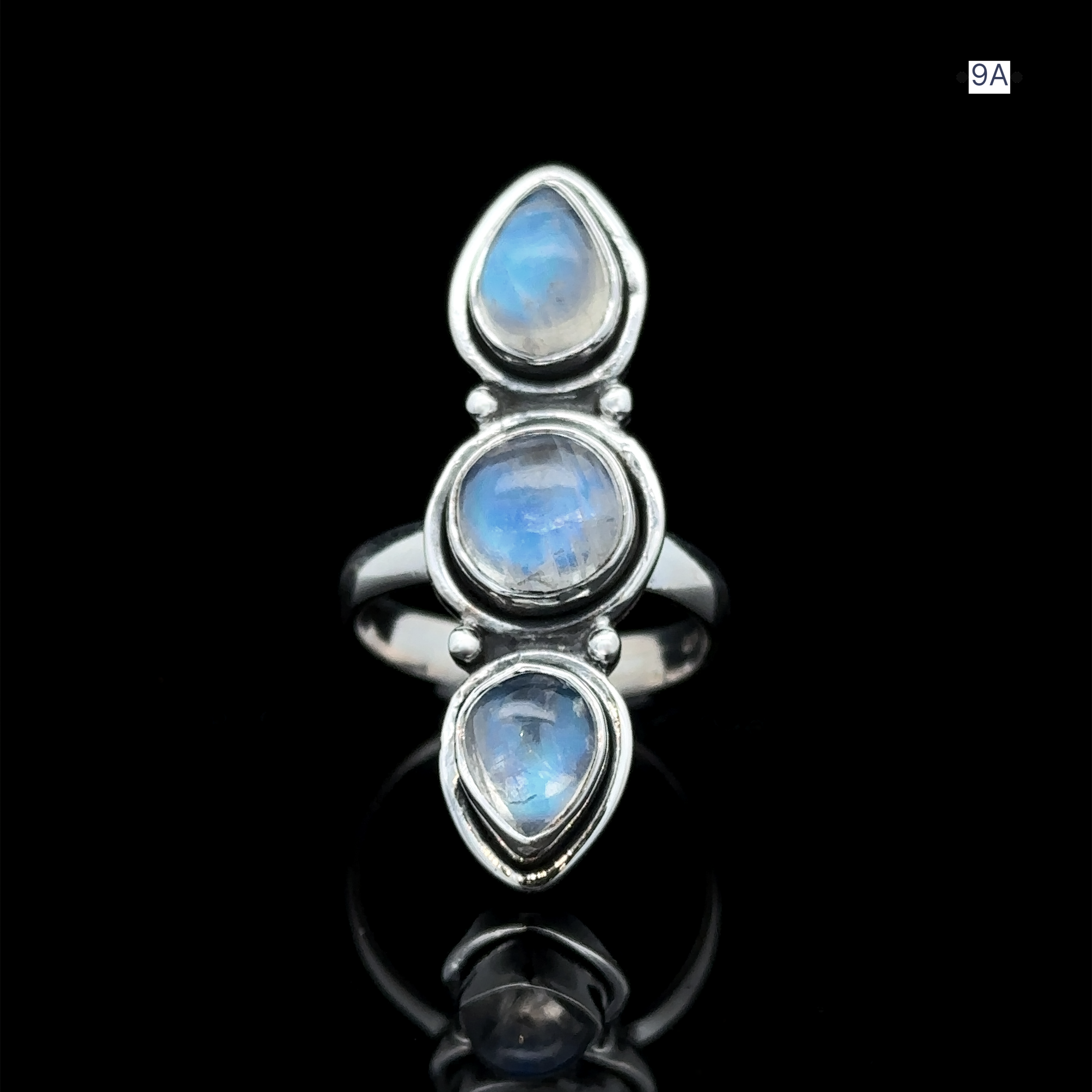 Triple Moonstone Ring crafted from sterling silver, featuring three vertically set teardrop-shaped gems. The blue and white hues evoke a sense of goddess energy when placed against a black backdrop.
