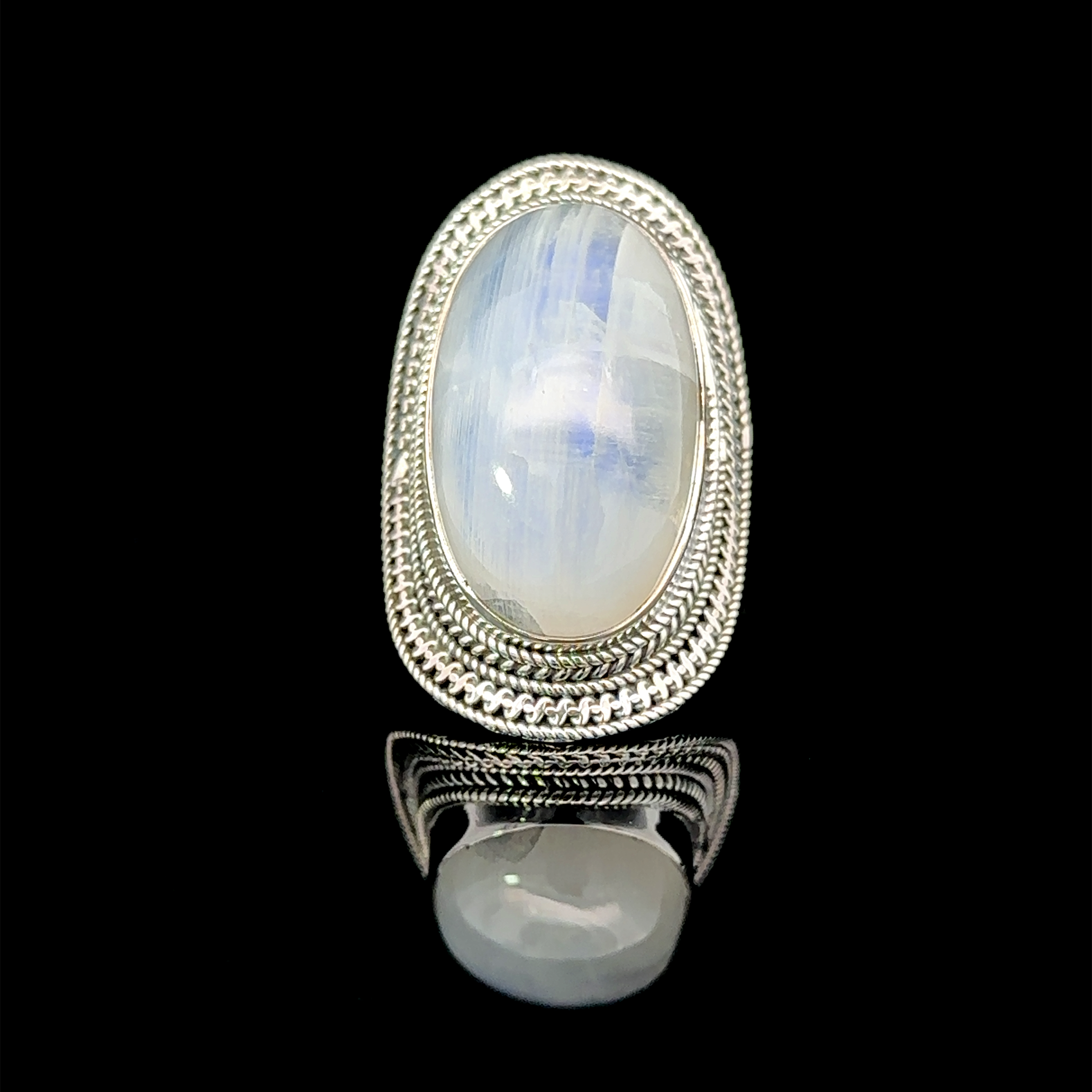 An **Large Oval Shield Gemstone Ring** set in a silver, intricately designed ring with a touch of bohemian flair is displayed against a black background.