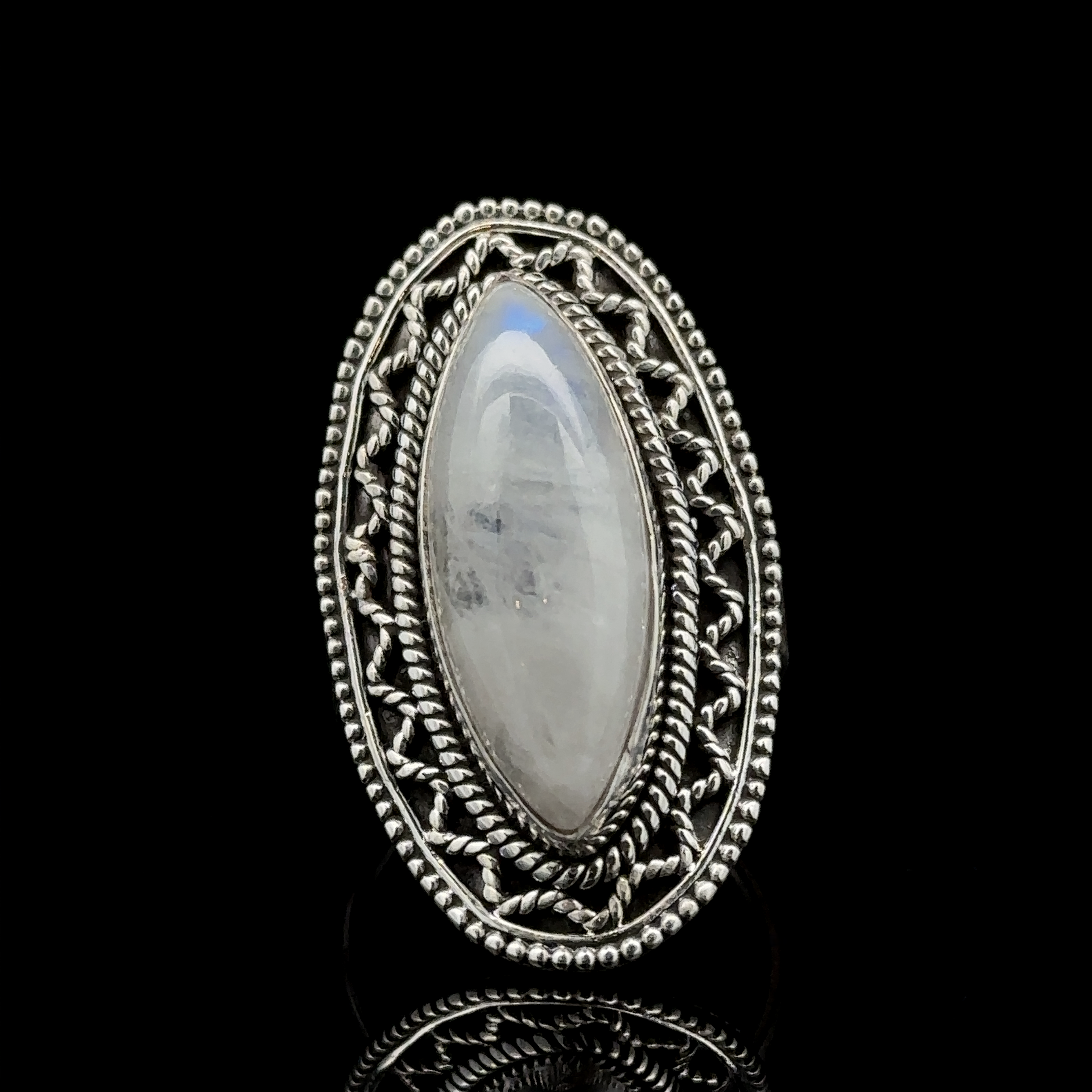 A Marquise Shaped Gemstone Ring With Vintage Shield Border with an elongated oval moonstone set in an intricately detailed filigree band against a black background, this piece offers a Bohemian twist to your style.