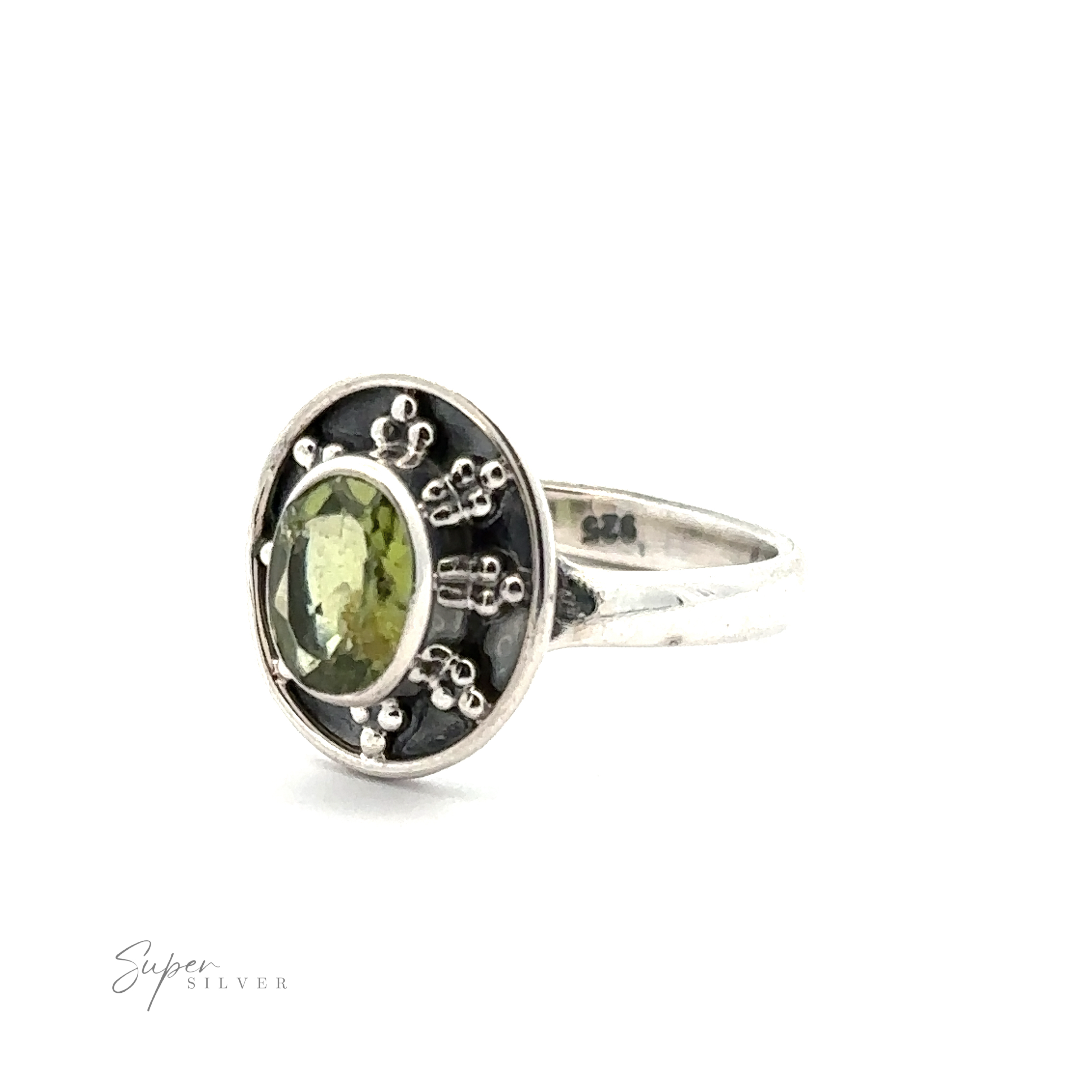 This vintage-inspired Oval Gemstone Ring with Ball and Disk Border boasts a green oval gemstone, set against a black background with intricate silver elements. The inside of the band is inscribed with "925".