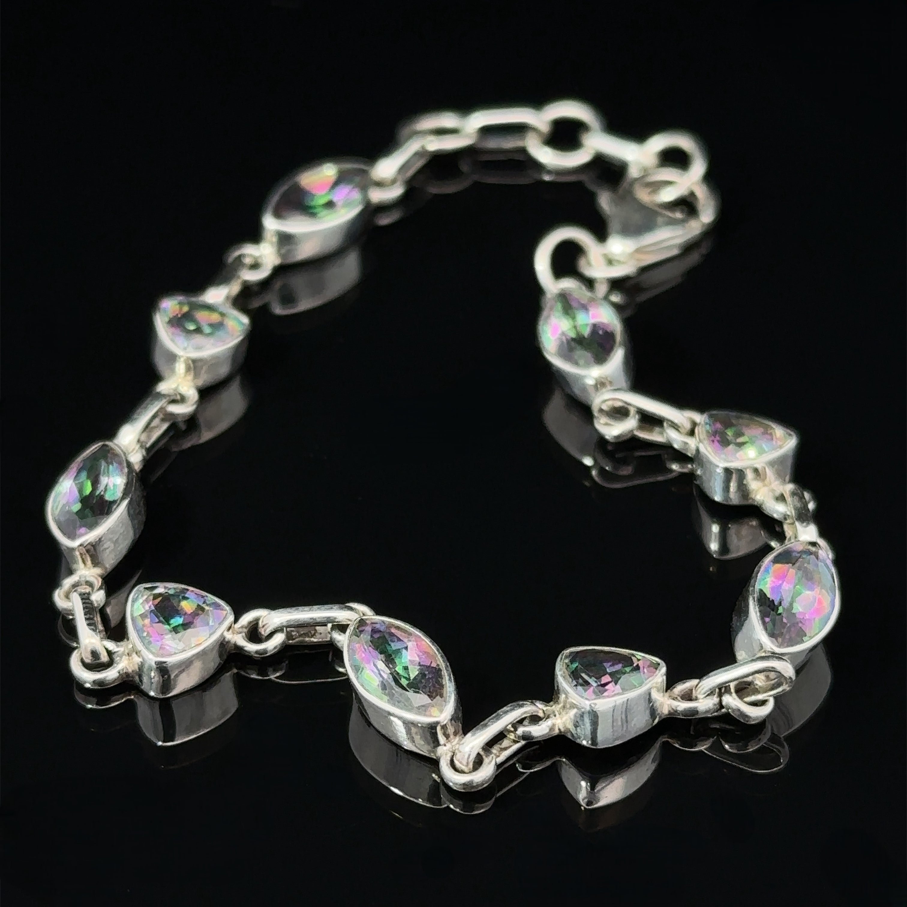 A sterling silver bracelet featuring marquise-shaped crystals with multicolored reflections, displayed on a black background, exudes the mystic allure of the Rainbow Mystic Topaz Marquise and Triangle Shape Link Bracelet.