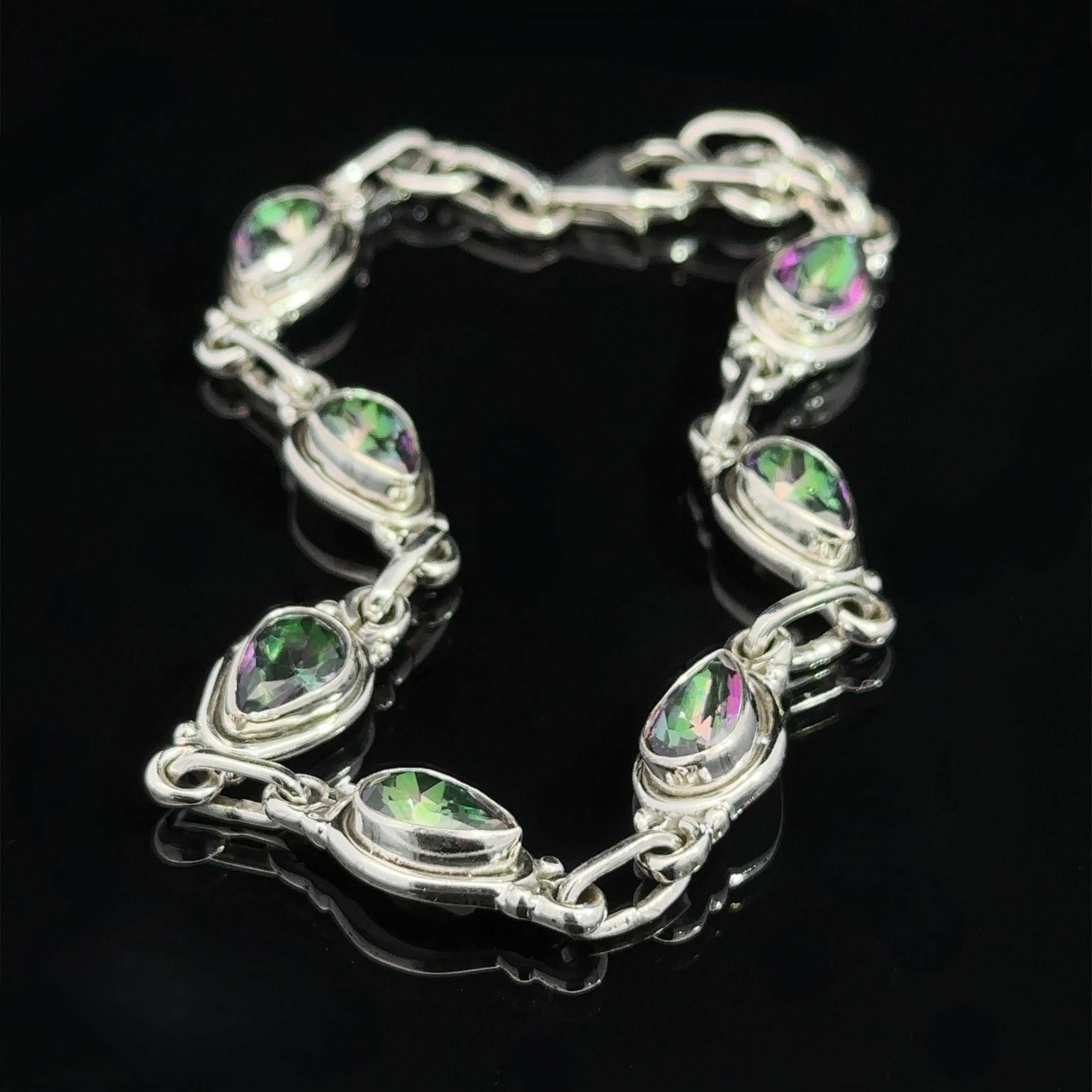 A Rainbow Topaz Bordered Teardrop Bracelet with nine teardrop-shaped, green and purple gemstones linked together, displayed on a black background.