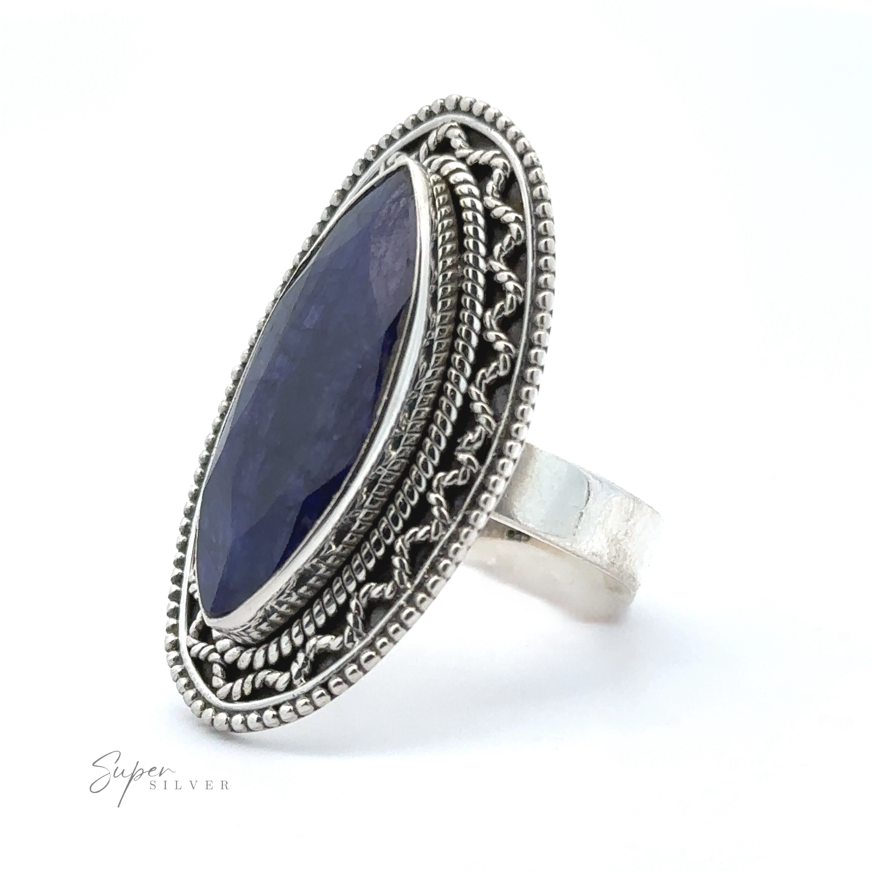 A Marquise Shaped Gemstone Ring With Vintage Shield Border with an oval-shaped, deep blue stone set in an intricate, decorative band. The brand name "Super Silver" is seen in the bottom left corner. This sterling silver piece adds a subtle Bohemian twist to any outfit.