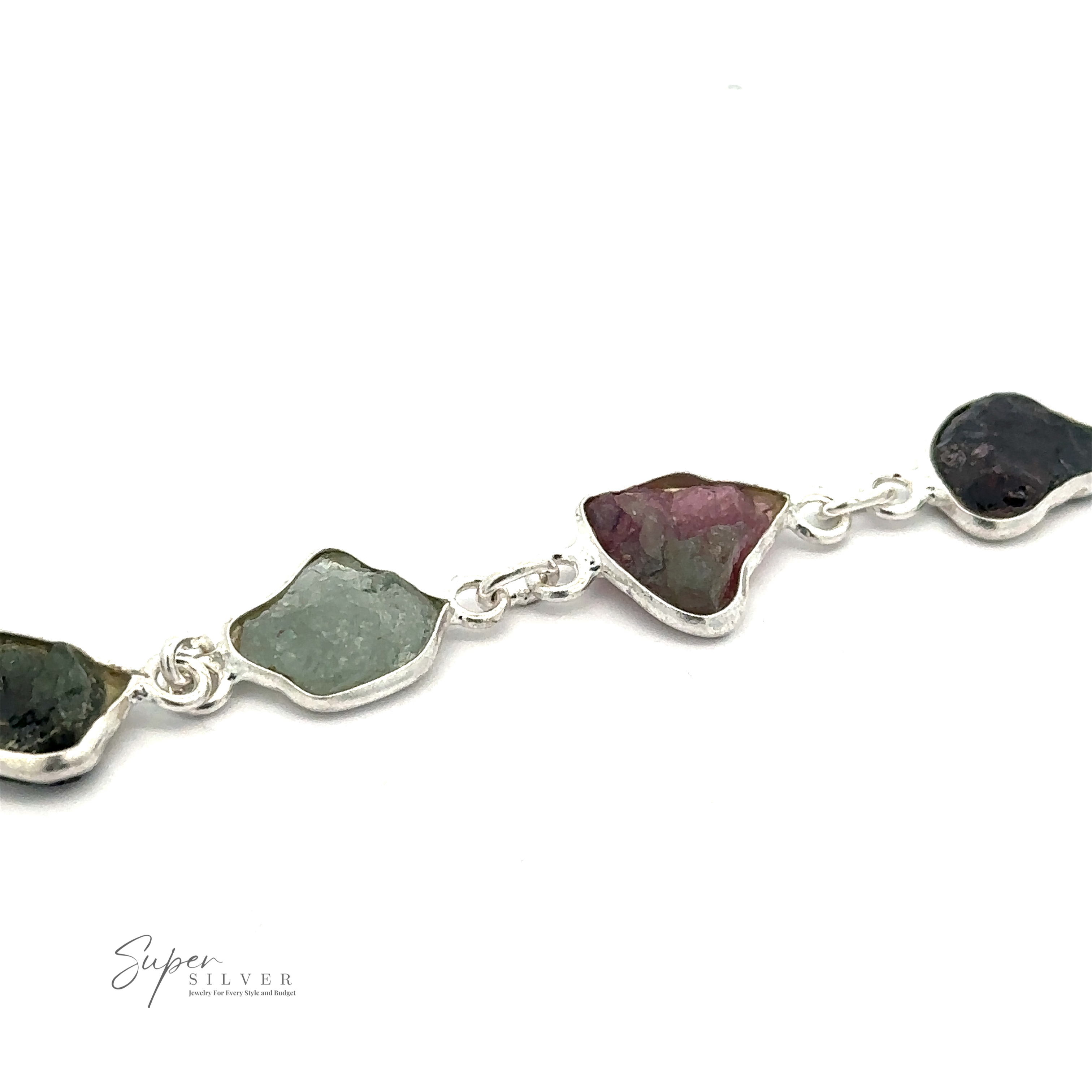 A Rough Tourmaline Bracelet featuring irregularly shaped, unpolished multicolored stones exudes earthy elegance. The rough tourmaline stones vary in color, including green, pink, and dark brown. This bracelet is from "Super Silver.