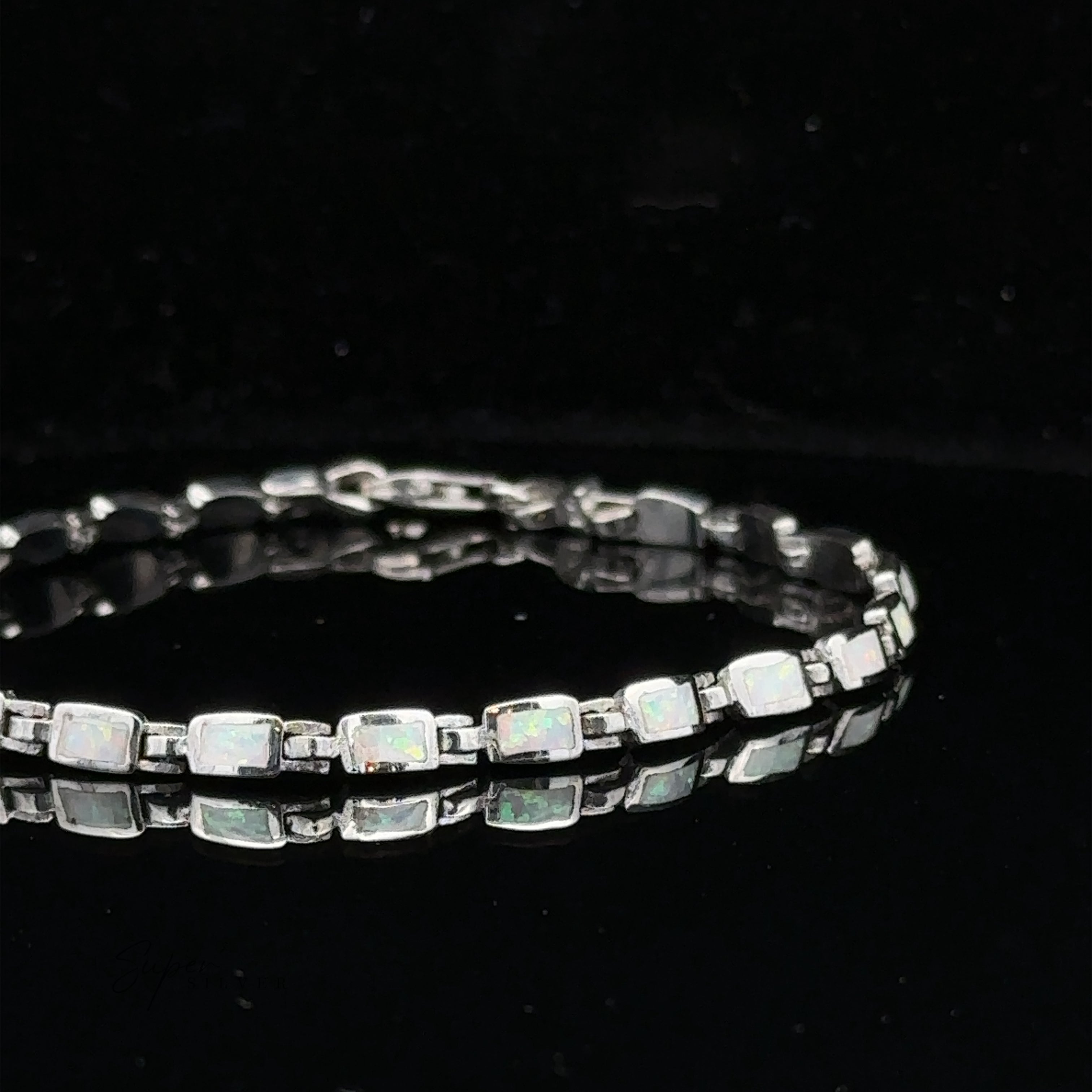 The Rectangle Lab-Created Opal Bracelet, featuring rectangular, lab-created opal stones set in individual sterling silver links, is showcased against a black background.