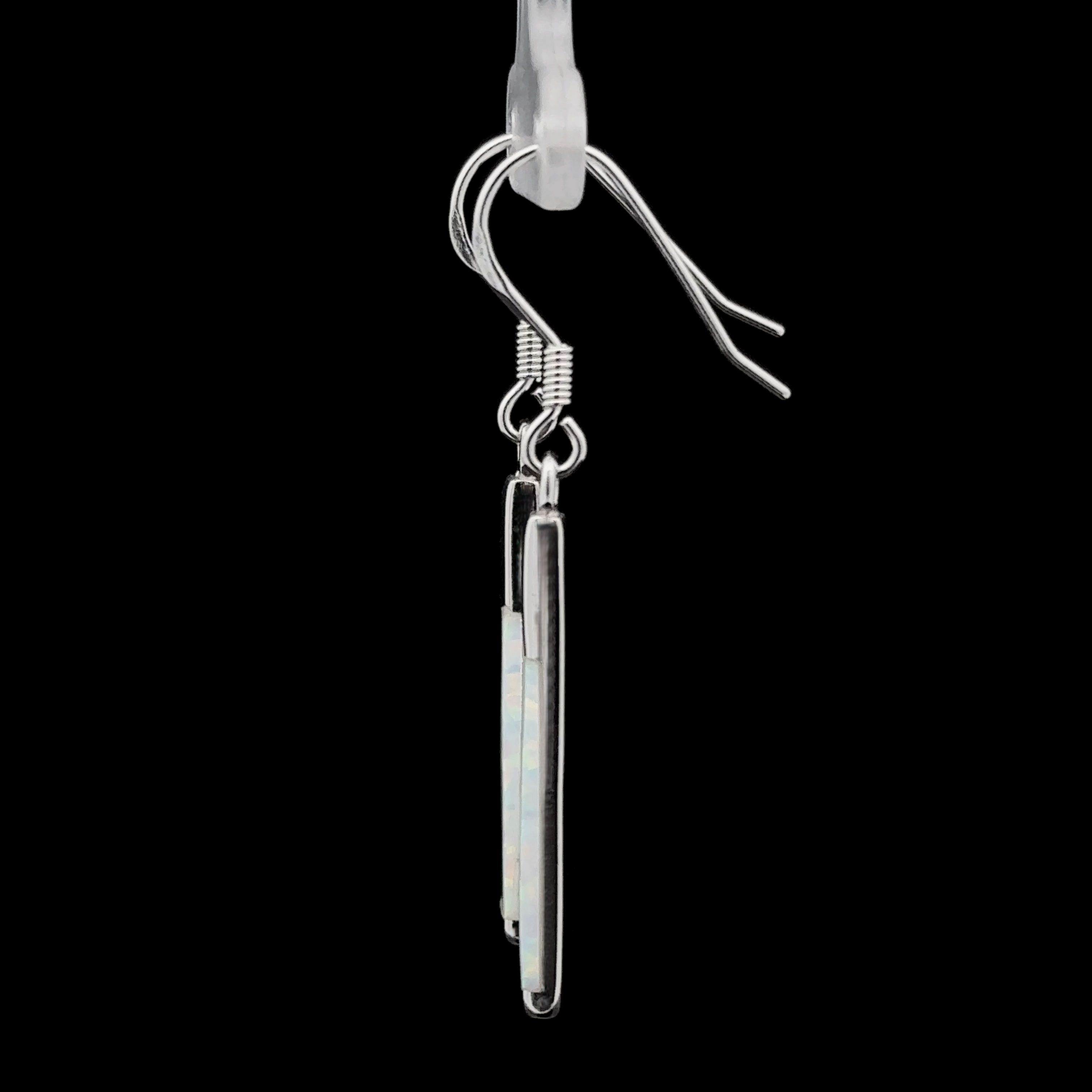 An Elegant Long Opal Earring, featuring a single silver drop with a thin, rectangular lab-created opal stone, hanging from a transparent hook against a black background—ideal for the contemporary artsy woman who appreciates modern flair.