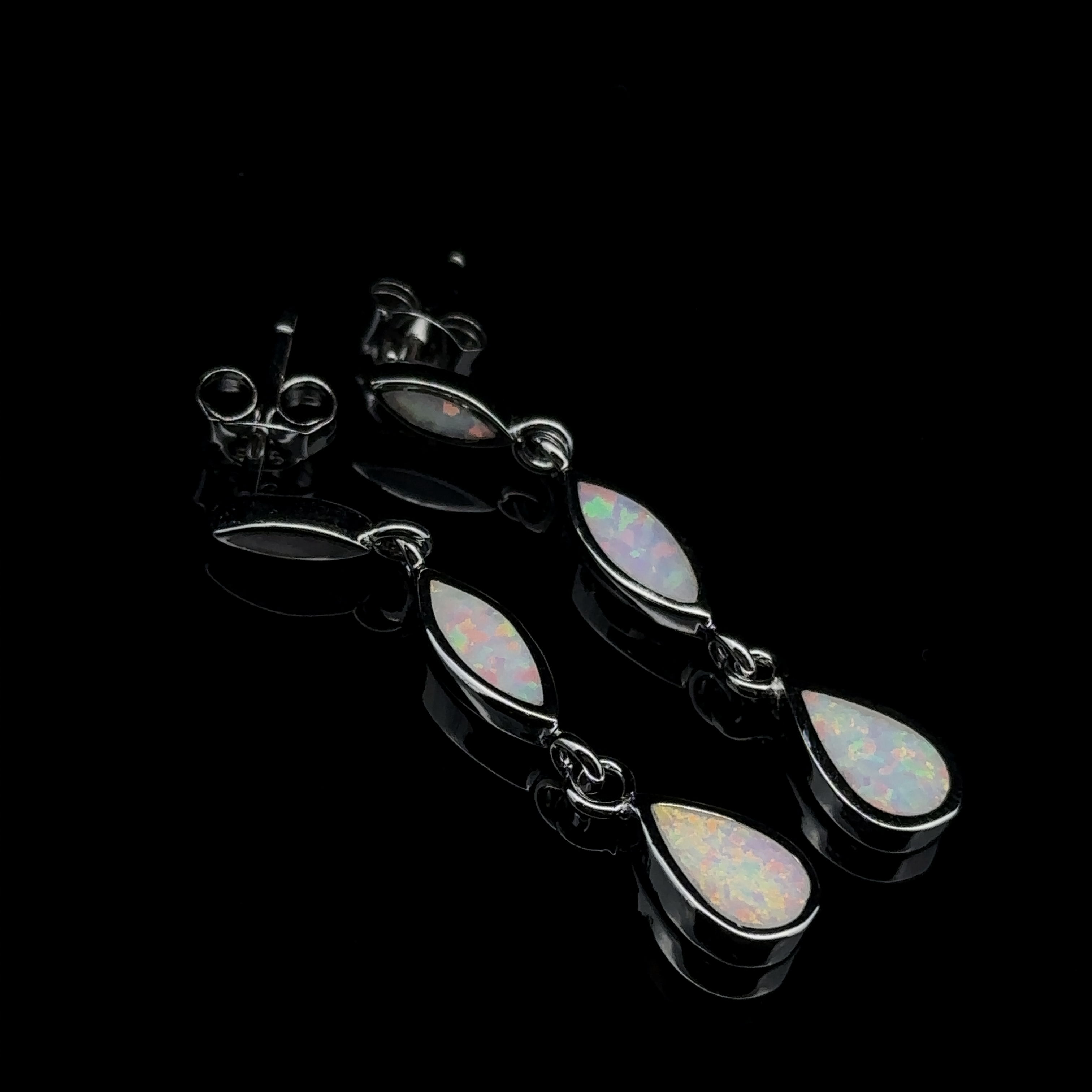 A pair of Elegant Lab-Created Opal Earrings with oval and teardrop-shaped stones, placed on a glossy black surface.