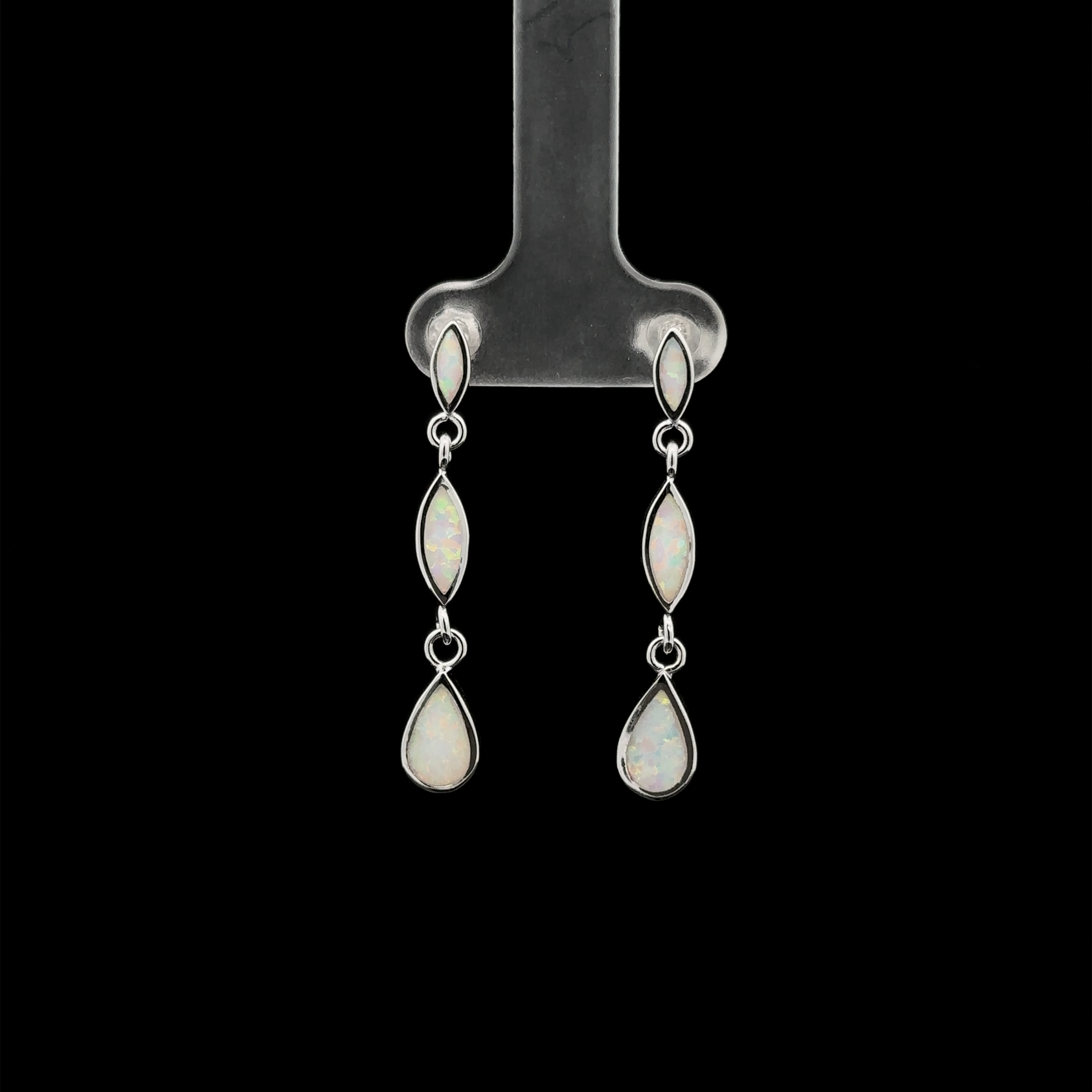 The Elegant Lab-Created Opal Earrings, featuring three linked, lab-created opal stones in an elegant oval shape, are displayed against a black background on a metal stand.
