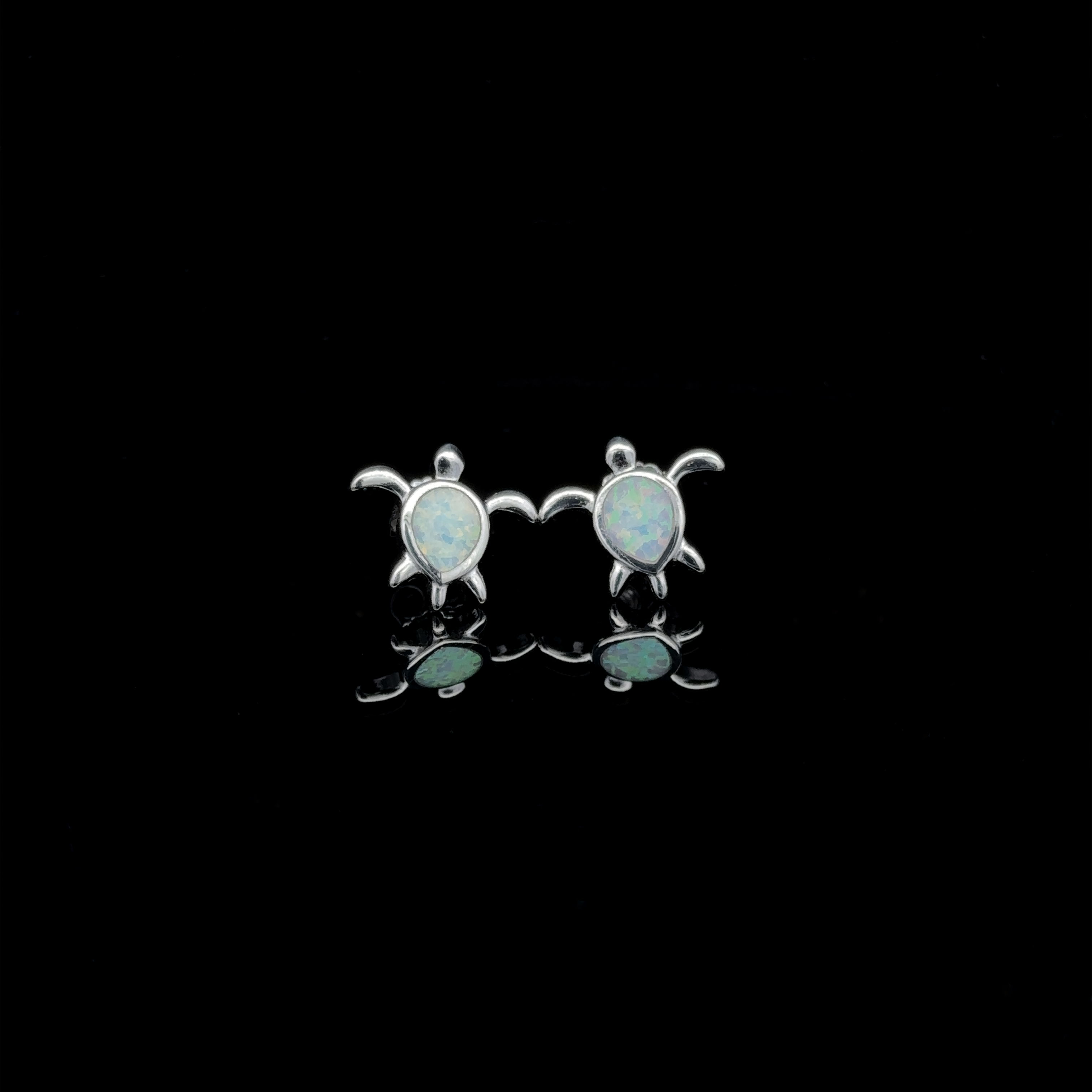 Pair of Simple Lab-Created Opal Turtle Studs in sterling silver, elegantly displayed on a reflective black surface.