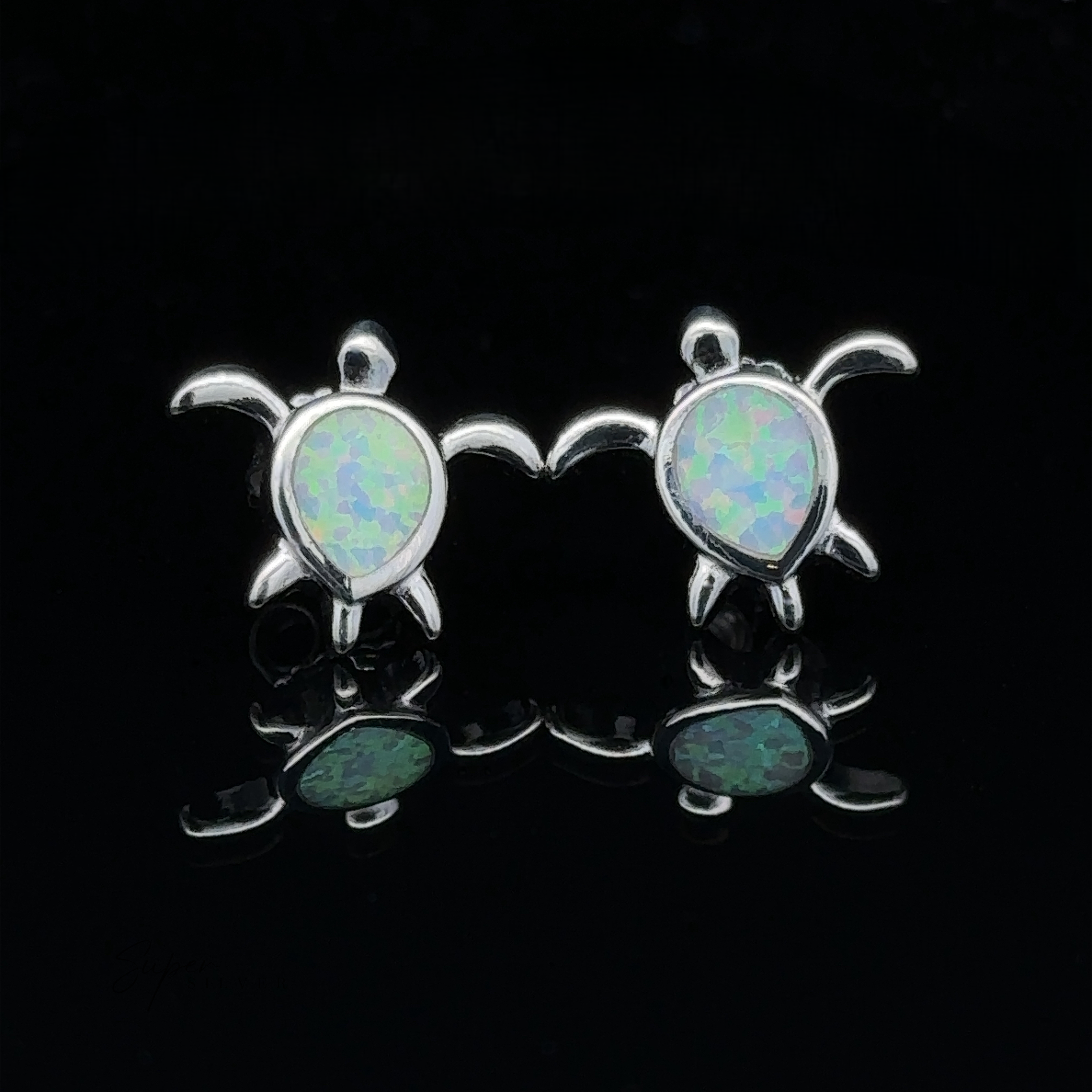 Introducing the Simple Lab-Created Opal Turtle Studs, a pair of sterling silver earrings featuring sea turtle designs with lab-created opal inlays set against a black background.