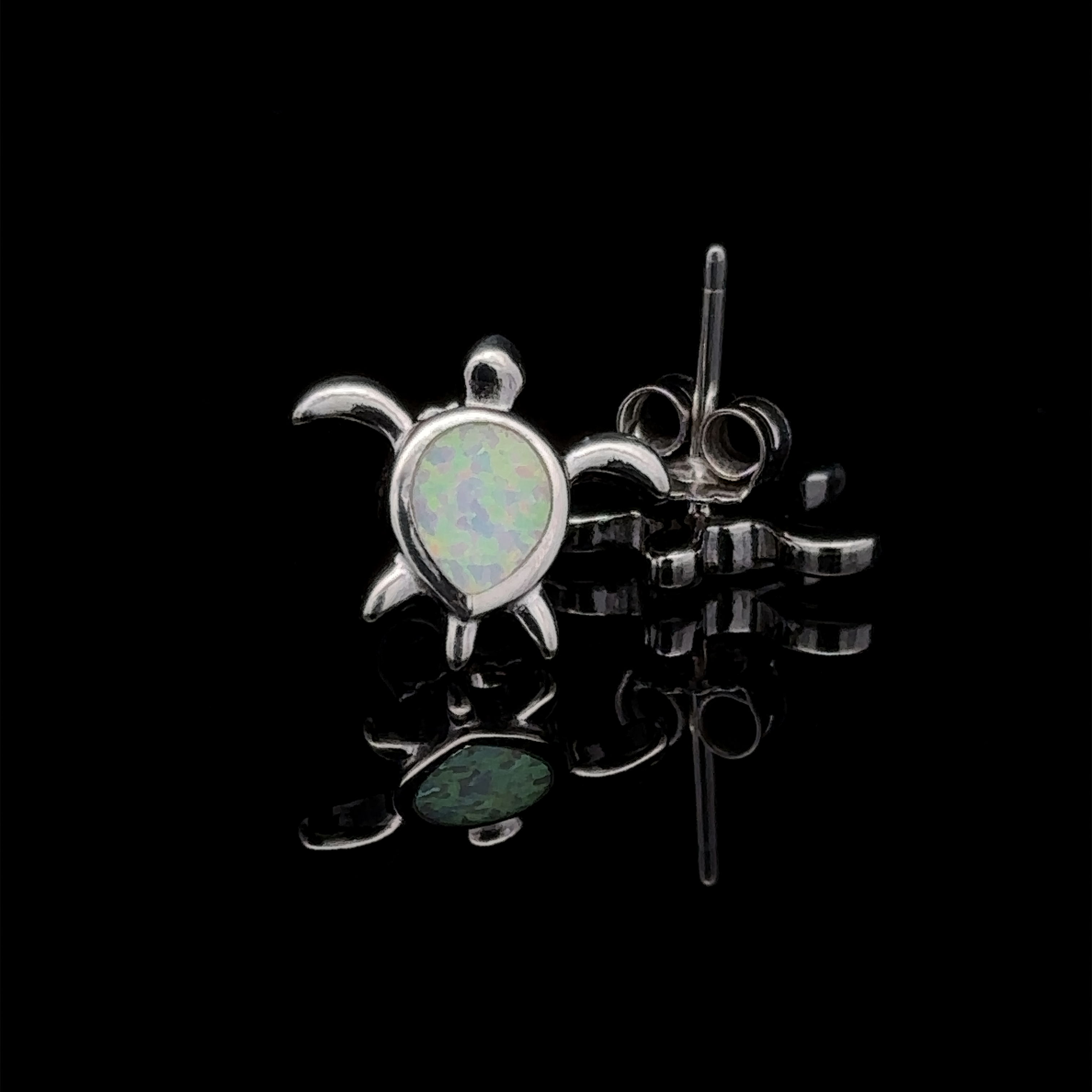A pair of Simple Lab-Created Opal Turtle Studs in sterling silver, showcased on a black reflective surface.